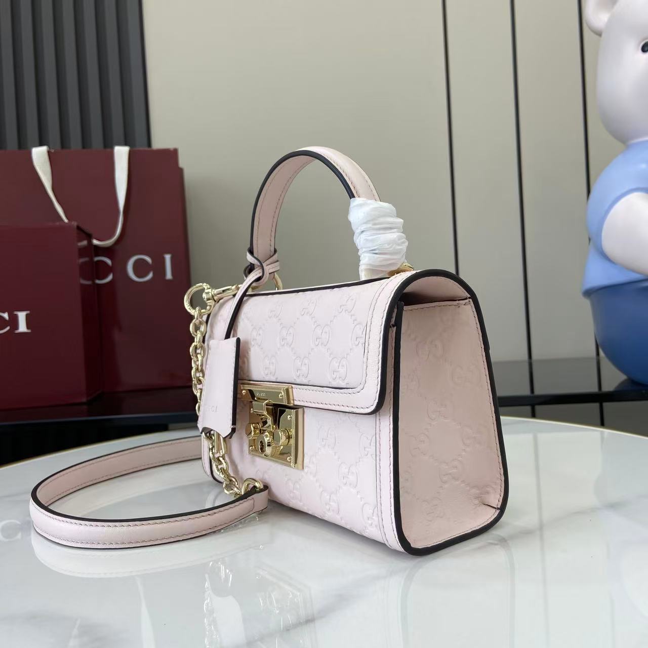 p640。《配全套原厂专柜包装》【新品】Padlock系列以现代廓形惊艳亮相2025早秋系列，解锁多种背携方式。此款式手提或斜挎皆宜，织带衬里致敬品牌标志性元素。
浅粉色GG字母交织图案涂层织物
浅粉色皮革滚边
浅金色调配件
浅粉色棉布衬里
内部：一个开口袋
外部：一个开口袋
提手（6厘米高）
可拆卸可调节皮革肩带（高度：57厘米 – 62厘米；长度：103厘米 – 123厘米）
挂锁锁扣，配有皮革钥匙扣
型号：848884。
尺寸：20厘米（宽）x 13厘米（高）x 8厘米（深）
重量：约0.6千克
颜色：浅粉色/压花。
意大利创作