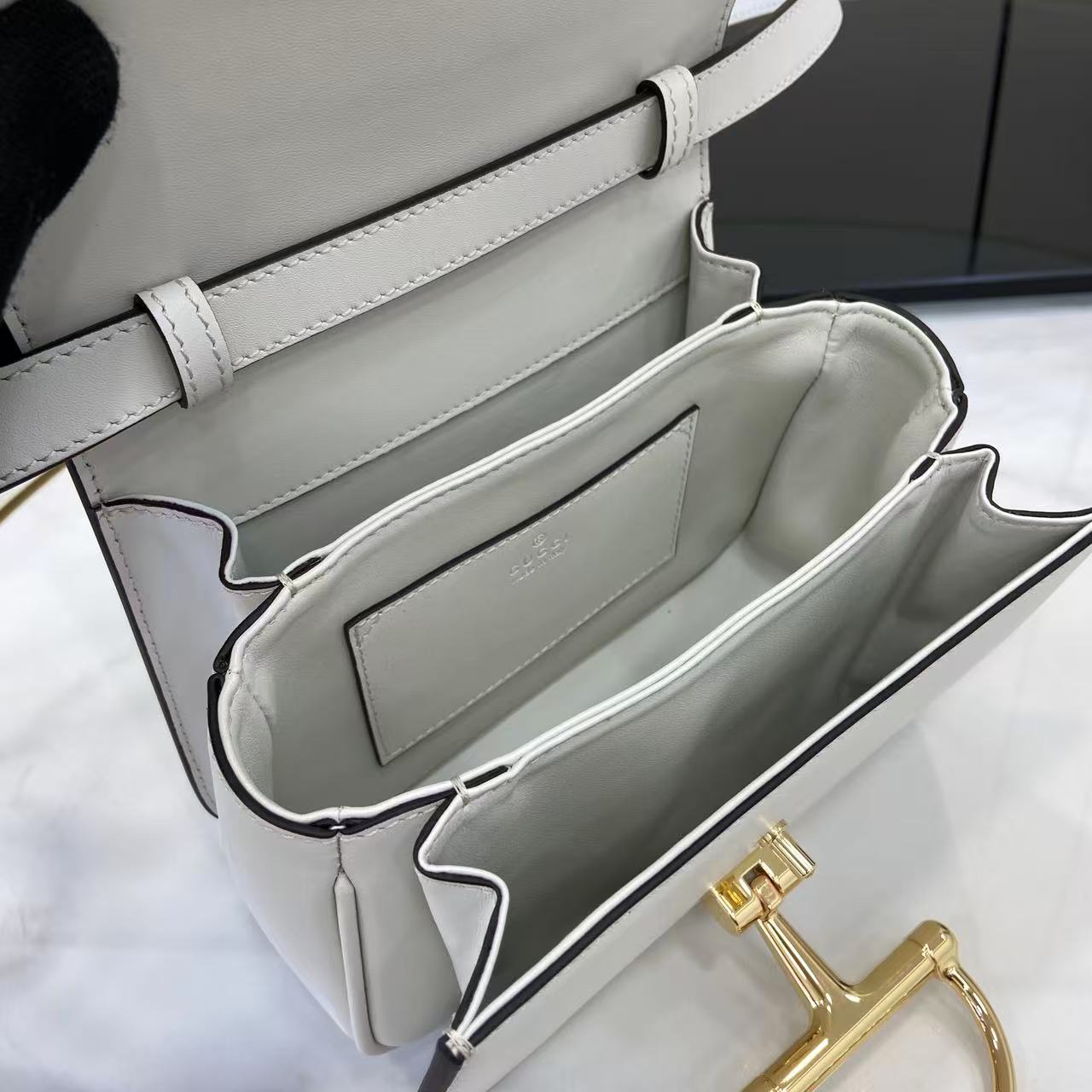 p750。《配全套原厂专柜包装》Gucci Siena系列焕新演绎品牌经典马衔扣元素，打造魅力手袋单品。这款手提包选用精细光面皮革匠心打造，挺括造型融蕴源自20世纪70年代的半马衔扣搭扣设计细节
白色光面皮革
金色调配件
白色皮革衬里
内部：3层接档，1个开口口袋
提手（6.5厘米高）
可拆卸可调节皮革肩带（高度：45厘米；长度：43厘米 - 47厘米）
半马衔扣造型按扣
型号：855536。
尺寸：19厘米（宽）x 13厘米（高）x 8.5厘米（深）
重量：约0.5千克
颜色：白色全皮。