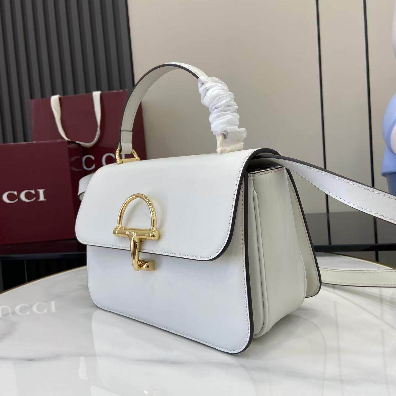 p810。《配全套原厂专柜包装》Gucci Siena系列焕新演绎品牌经典马衔扣元素，打造魅力手袋单品。这款手提包选用精细光面皮革匠心打造，挺括造型融蕴源自20世纪70年代的半马衔扣搭扣设计细节
白色光面皮革
金色调配件
白色皮革衬里
内部：3层接档，1个拉链口袋
提手（8厘米高）
可拆卸可调节皮革肩带（高度：46厘米 - 52厘米；长度：142厘米）
半马衔扣造型按扣
型号：855535。
尺寸：25.5厘米（宽）x 16厘米（高）x 9厘米（深）
重量：约0.75千克
颜色：白色全皮。