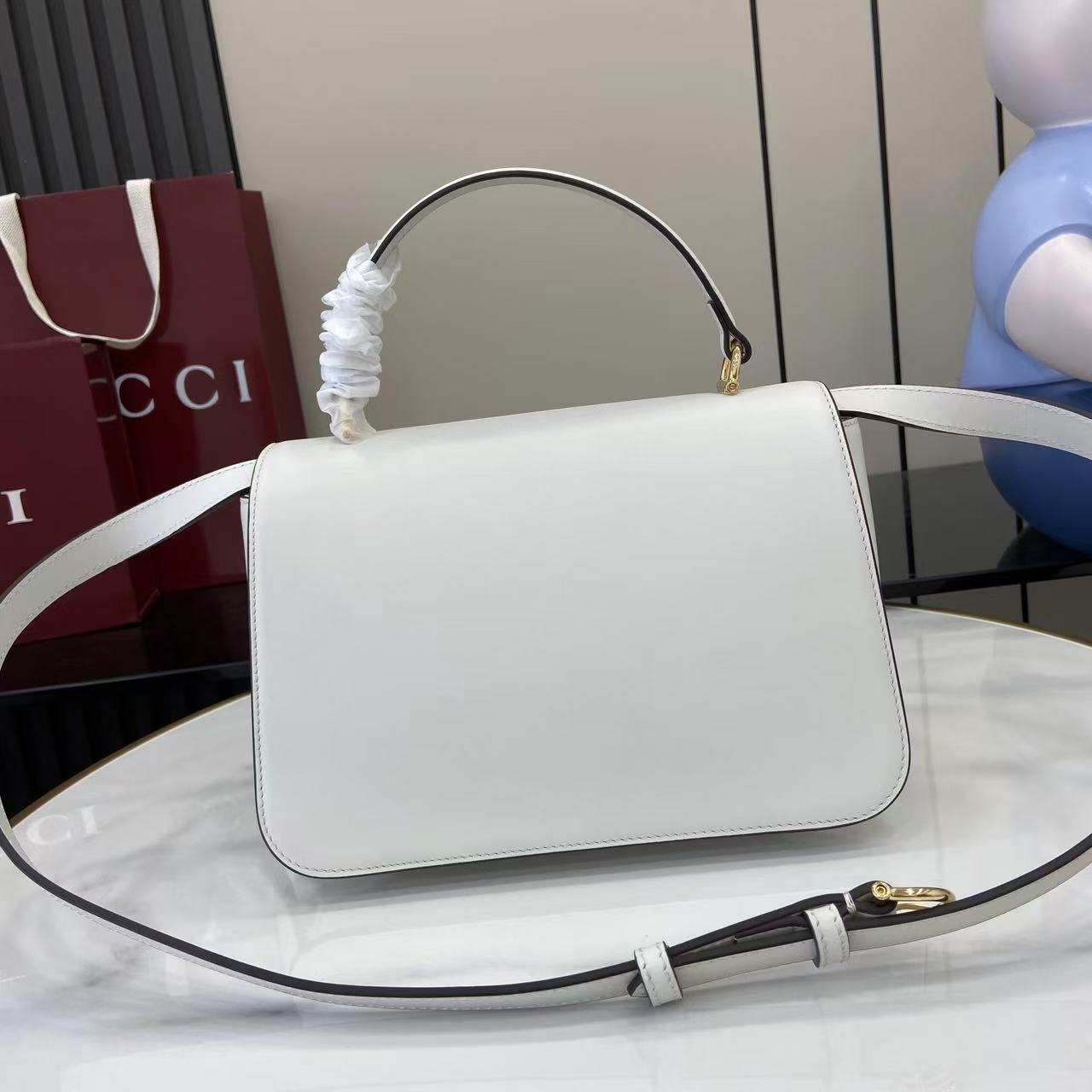 p810。《配全套原厂专柜包装》Gucci Siena系列焕新演绎品牌经典马衔扣元素，打造魅力手袋单品。这款手提包选用精细光面皮革匠心打造，挺括造型融蕴源自20世纪70年代的半马衔扣搭扣设计细节
白色光面皮革
金色调配件
白色皮革衬里
内部：3层接档，1个拉链口袋
提手（8厘米高）
可拆卸可调节皮革肩带（高度：46厘米 - 52厘米；长度：142厘米）
半马衔扣造型按扣
型号：855535。
尺寸：25.5厘米（宽）x 16厘米（高）x 9厘米（深）
重量：约0.75千克
颜色：白色全皮。