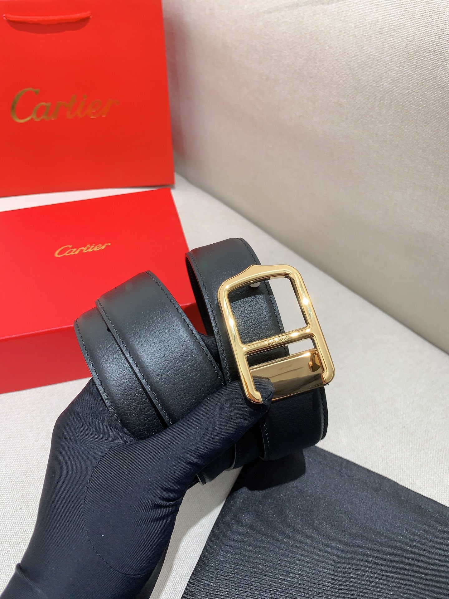  卡地亚针扣式皮带，Cartier标志。黑色与棕色牛皮双面皮带，浮雕“Cartier”标志。尺寸：宽35