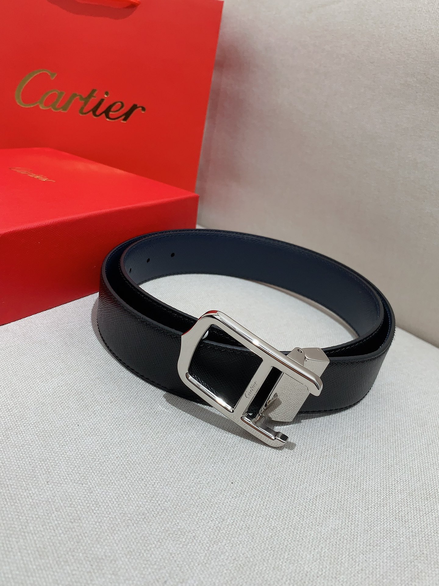  卡地亚针扣式皮带，Cartier标志。黑色与棕色牛皮双面皮带，浮雕“Cartier”标志。尺寸：宽35