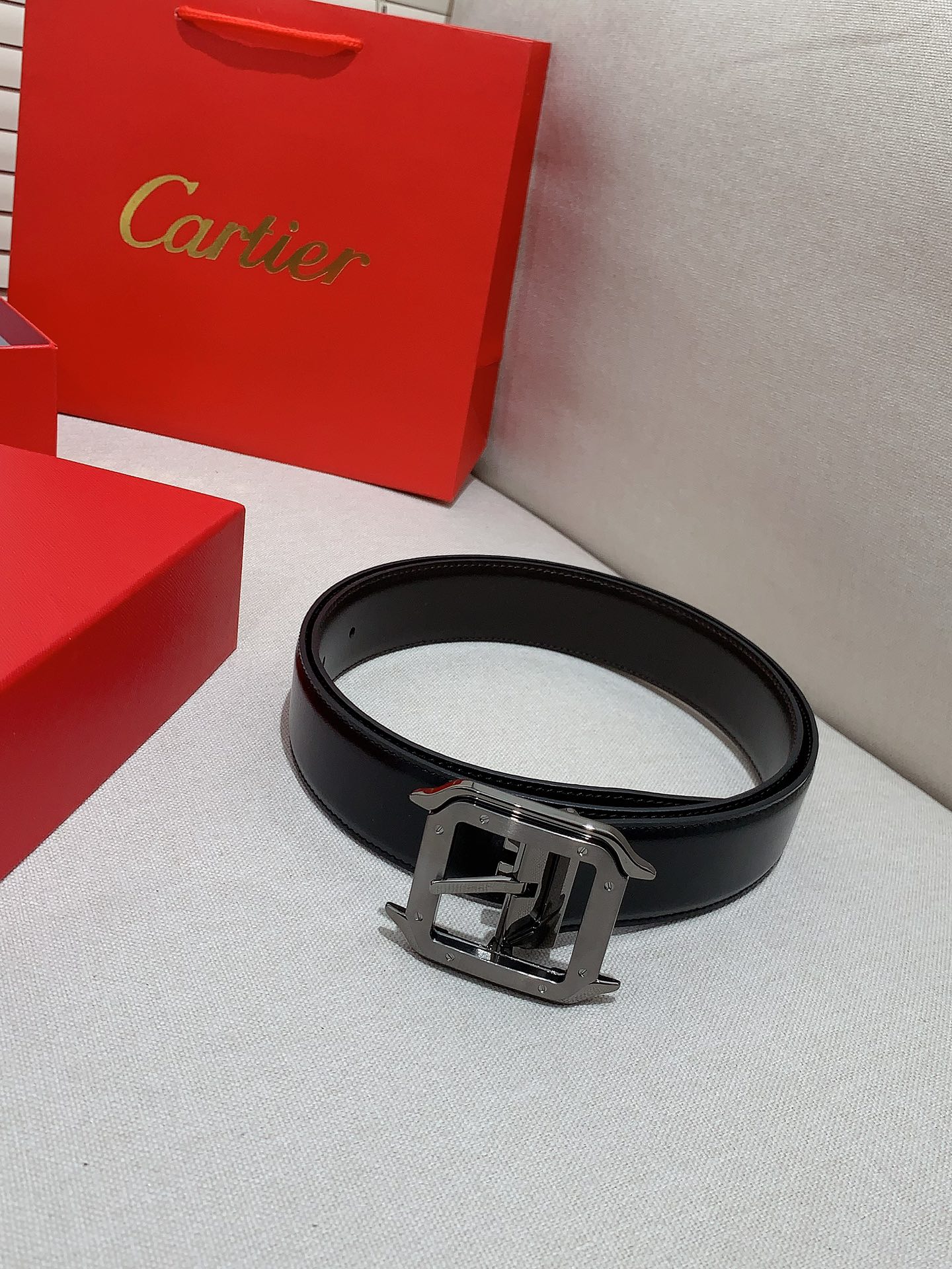  卡地亚针扣式皮带，Cartier标志。黑色与棕色牛皮双面皮带，浮雕“Cartier”标志。尺寸：宽35