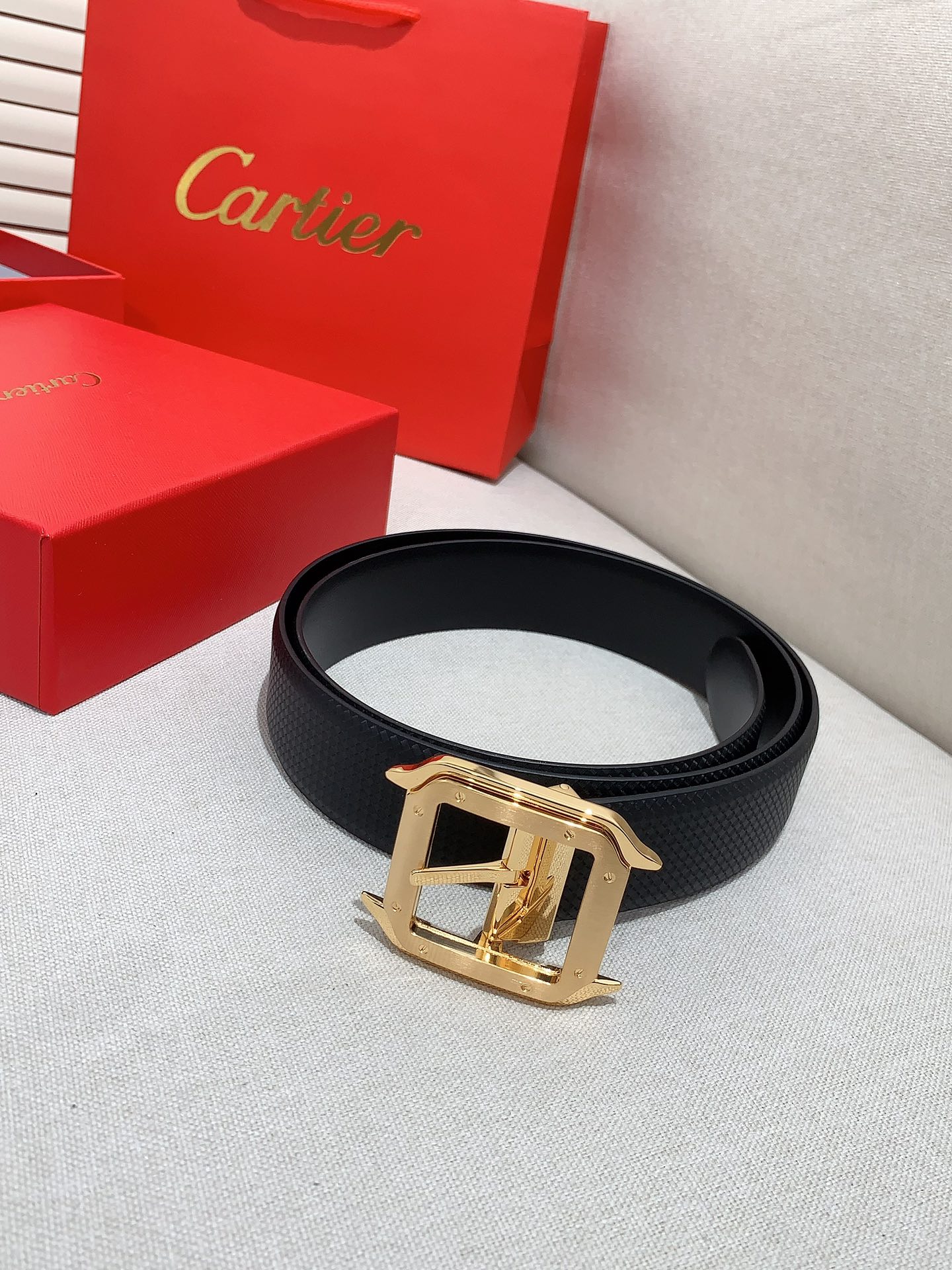  卡地亚针扣式皮带，Cartier标志。黑色与棕色牛皮双面皮带，浮雕“Cartier”标志。尺寸：宽35