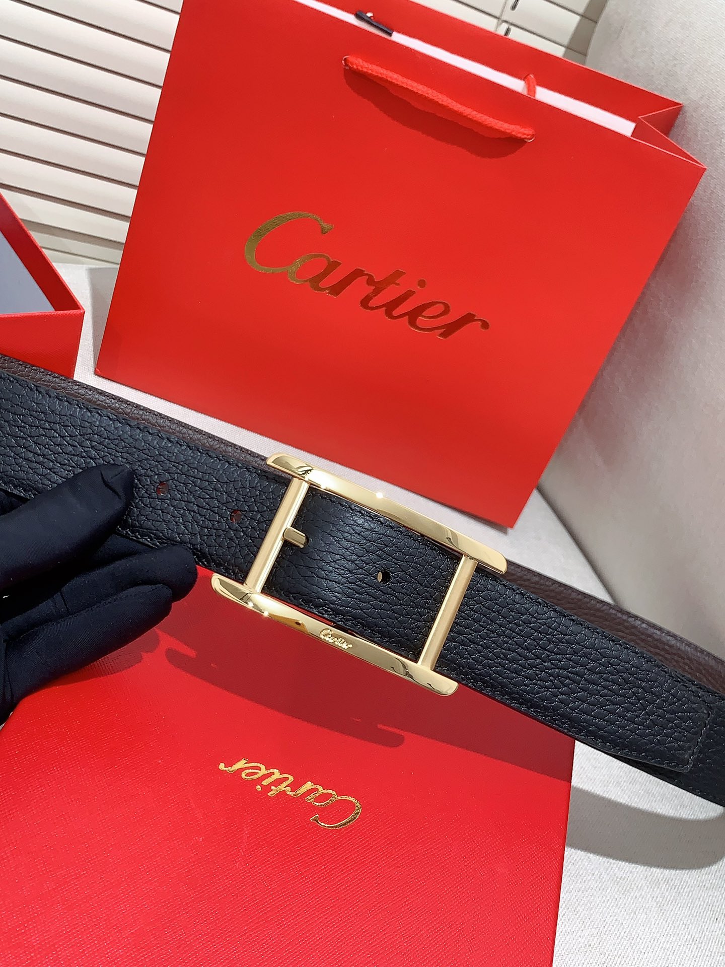  卡地亚针扣式皮带，Cartier标志。黑色与棕色牛皮双面皮带，浮雕“Cartier”标志。尺寸：宽35