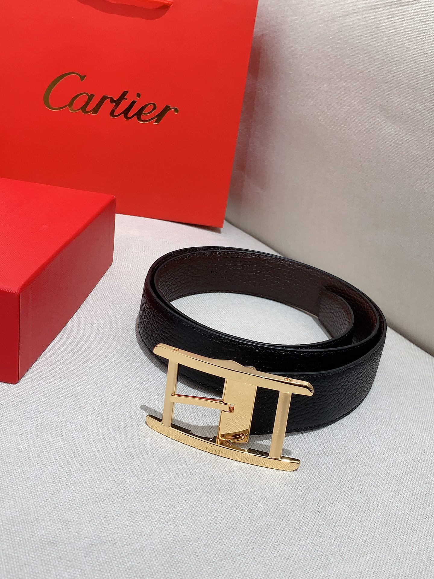  卡地亚针扣式皮带，Cartier标志。黑色与棕色牛皮双面皮带，浮雕“Cartier”标志。尺寸：宽35