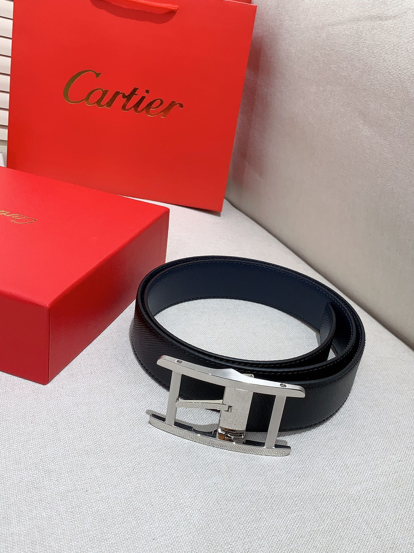  卡地亚针扣式皮带，Cartier标志。黑色与棕色牛皮双面皮带，浮雕“Cartier”标志。尺寸：宽35