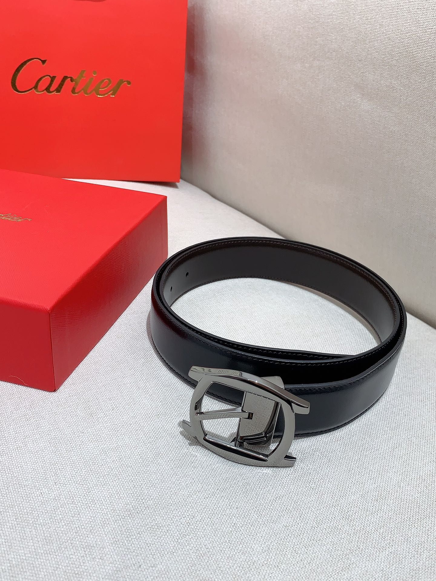  卡地亚针扣式皮带，Cartier标志。黑色与棕色牛皮双面皮带，浮雕“Cartier”标志。尺寸：宽35