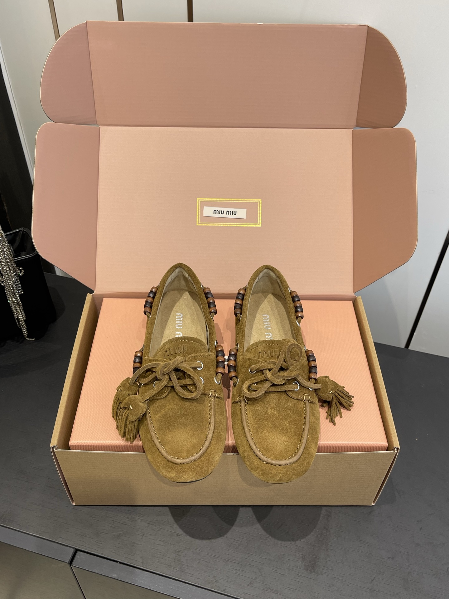 NO:592326,Miu Miu 25FW deck shoes suede double-tassel slip-on loafers. The upper is made of suede material. It feels soft and has a retro texture. The side of the shoe is decorated with beading elements and is fixed by metal eyelets. The workmanship is exquisite and adds bohemian details. There is a tassel lace on the toe. The combination of lace knots and tassels enhances the retro hippie style. The flat design ensures a comfortable foot feel. The shoe shape is loose and does not squeeze the feet. Suitable for daily long-term wear.  The softness of suede leather further enhances wearing comfort. The insole of the shoe is printed with a clear 'miu miu' brand logo to highlight brand recognition and texture. Cow suede upper, cowhide lining, rubber outsole, size 35-40 (40 customized), loafers, miumiu, loafers, cowhide, chamois leather19860909Miu Miu 缪缪 25FW deck shoes 麂皮双流苏一脚蹬乐福鞋 鞋面采用反绒皮材质 触感柔软且自带复古质感 鞋侧装饰有串珠元素 通过金属孔眼固定 工艺精致 增添波西米亚风细节 鞋头处设有流苏系带 系带结与流苏的组合强化了复古嬉皮风格 平底设计保障舒适脚感 鞋型宽松不挤脚 适合日常长时间穿着 反绒皮的柔软度进一步提升穿着舒适度 鞋内底印有清晰的“miu miu”品牌logo 彰显品牌辨识度与质感 鞋面牛反绒 内里牛皮 橡胶大底 码数35-40（40定做）,乐福鞋,miumiu,loafers,cowhide,chamois leather,Women's Shoes