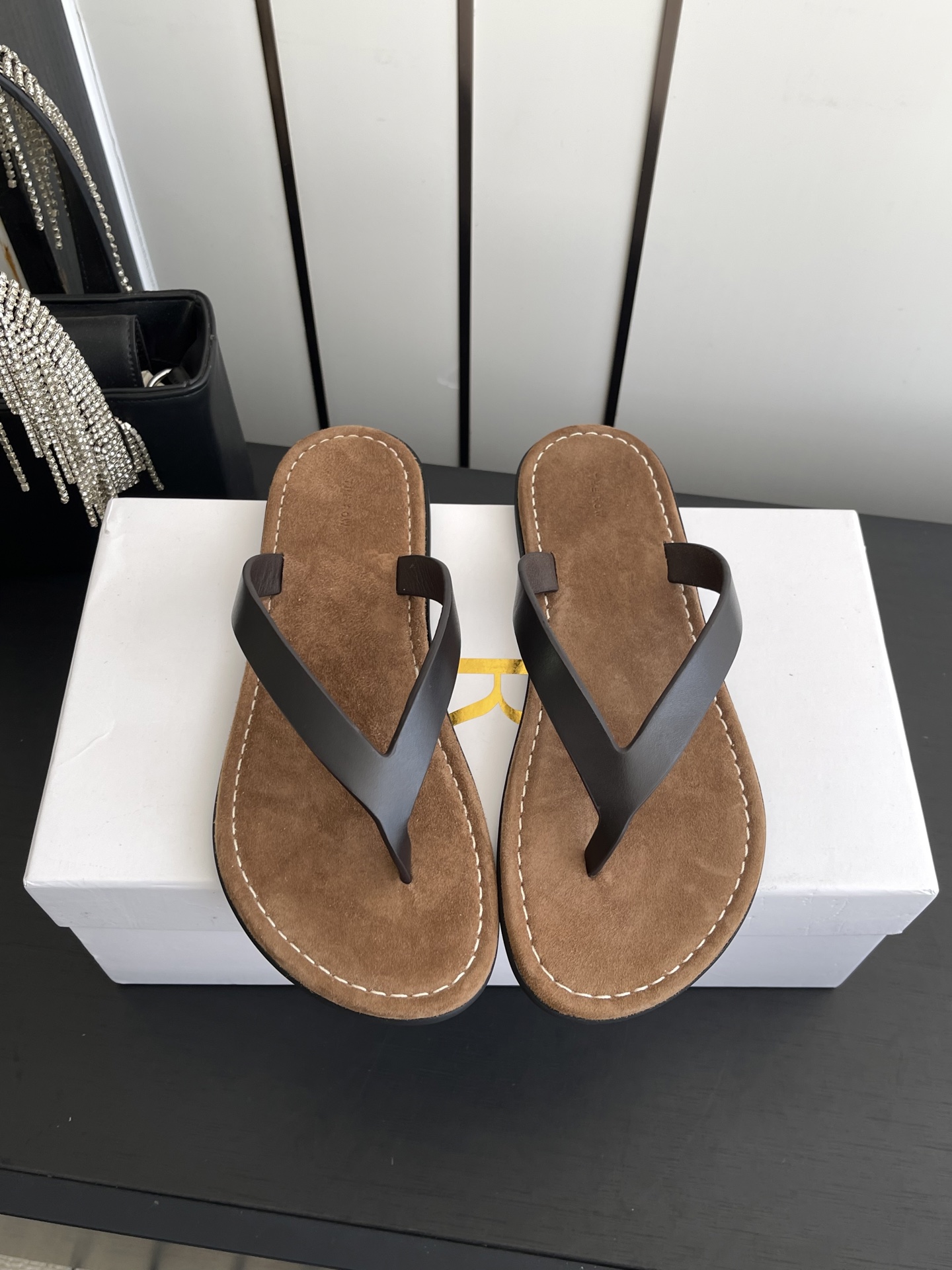 NO:874067,The Row's minimalist old-money style flat flip-flops. The ultimate minimalist aesthetic completely abandons fancy decorations. It only uses a delicate leather strap + light khaki suede/cowhide footbed. The clean lines have a high-end sense of relaxation. It perfectly fits The Row's consistent 'logo-free luxury' concept.  Equipped with non-slip and wear-resistant rubber flat soles, it can be used for daily shopping and beach vacations. Size 35-40 (customized for 40), split-toe shoes, cowhide, chamois leather19860909The Row 极简老钱风平底人字拖  极致极简美学完全抛弃了花哨的装饰 只用一条细腻的皮革带+浅卡其色麂皮/牛皮鞋床 干净利落的线条 自带高级松弛感 完美契合The Row一贯的“无logo奢华”理念鞋床大多采用翻毛麂皮脚感软糯亲肤 长时间穿也不会磨脚 夹趾带做了软化处理 搭配防滑耐磨的橡胶平底 日常逛街 海边度假都能hold住 码数35-40（40定做）,分趾鞋,cowhide,chamois leather,Women's Shoes