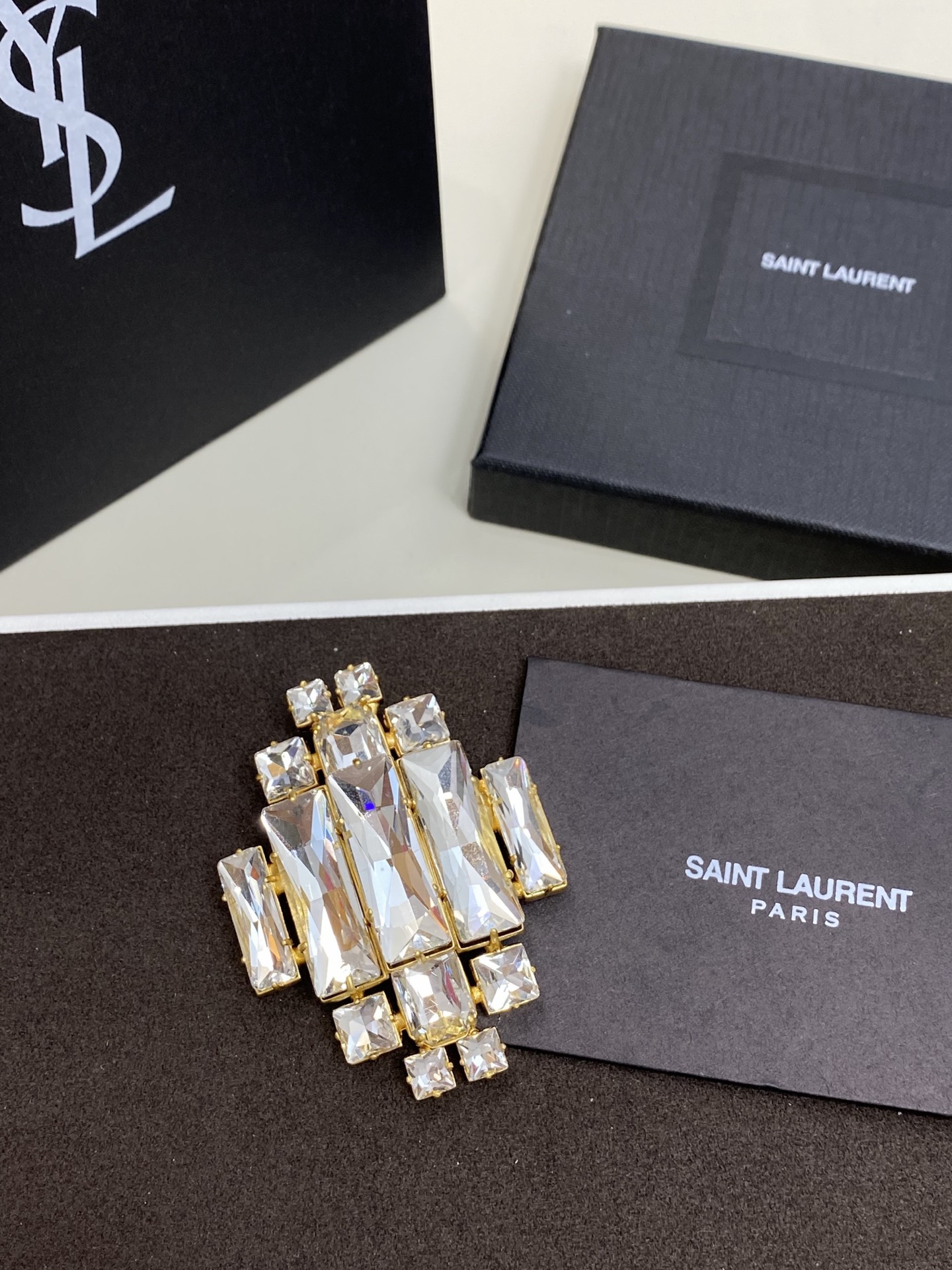 NO:714491,Ysl geometric crystal brooch. Rectangular and square crystals are staggered with a gold frame, just like solidified starlight pinned to the lapel. It can be embellished on the collar of a suit, the lapel of a coat or the corner of a silk scarf, instantly brightening up a simple outfit and perfectly balancing elegance and magnificence., saint laurent, business suit, brooch, breastpin, gold, Cardia high-end jewelry19860909Ysl几何水晶胸针 长方与方形水晶以黄金框架错落拼接,如同把凝固的星光别在衣襟.可点缀西装领口、大衣翻领或丝巾一角,瞬间点亮简约穿搭,让优雅与华丽在方寸间完美平衡.,,saint laurent,business suit,brooch，breastpin,gold,卡迪亚高端饰品,Jewelry