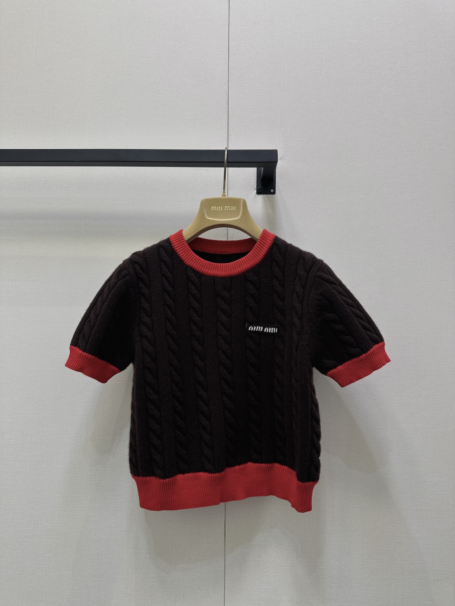 NO:564584,Miumi* 25Fw early autumn new style logo slim fit twist round neck wool short-sleeved sweater丨Original development!  High quality production!  High-quality wool fabrics are selected, and the twist knitting process gives the body a full and three-dimensional texture. It not only retains the warmth and softness of wool, but also adapts to the early autumn climate because of the short-sleeved version. It is worn next to the skin with the gentle care of wool. Visually, it outlines a graceful figure with its slim tailoring. It cleverly blends the laziness of French retro with the delicateness of a girl. The contrasting red and brown details are very beautiful.  Highly identifiable, the red hemming on the round neck and cuffs is like a bright note jumping on the dark brown background. The exquisite logo embroidery on the chest low-key highlights the identity of the luxury brand, allowing every detail to hide the brand's ultimate pursuit of texture. Available in stock, S/M/L, large quantities, real shots,, miumiu, T-shirt, alexander  wang19860909Miumi* 25Fw早秋新款 徽标修身麻花圆领羊毛短袖针织衫丨原版开发！高版出品！甄选高品质羊毛面料,麻花针织工艺赋予衣身饱满立体的纹理感,既保留羊毛的温暖软糯,又因短袖版型适配早秋气候,贴肤穿着是羊毛的轻柔呵护,视觉上却凭借修身剪裁勾勒出曼妙身形,将法式复古的慵懒与少女的娇俏巧妙糅合.红棕撞色细节极具辨识度,圆领与袖口的红色包边,像一抹亮色音符跳跃在深棕底色上,胸前精致的徽标刺绣,低调彰显奢牌身份,让每一处细节都藏着品牌对质感的极致追求.现货发售S/M/L大货实拍,,miumiu,T-shirt,alexander wang,Women's clothing
