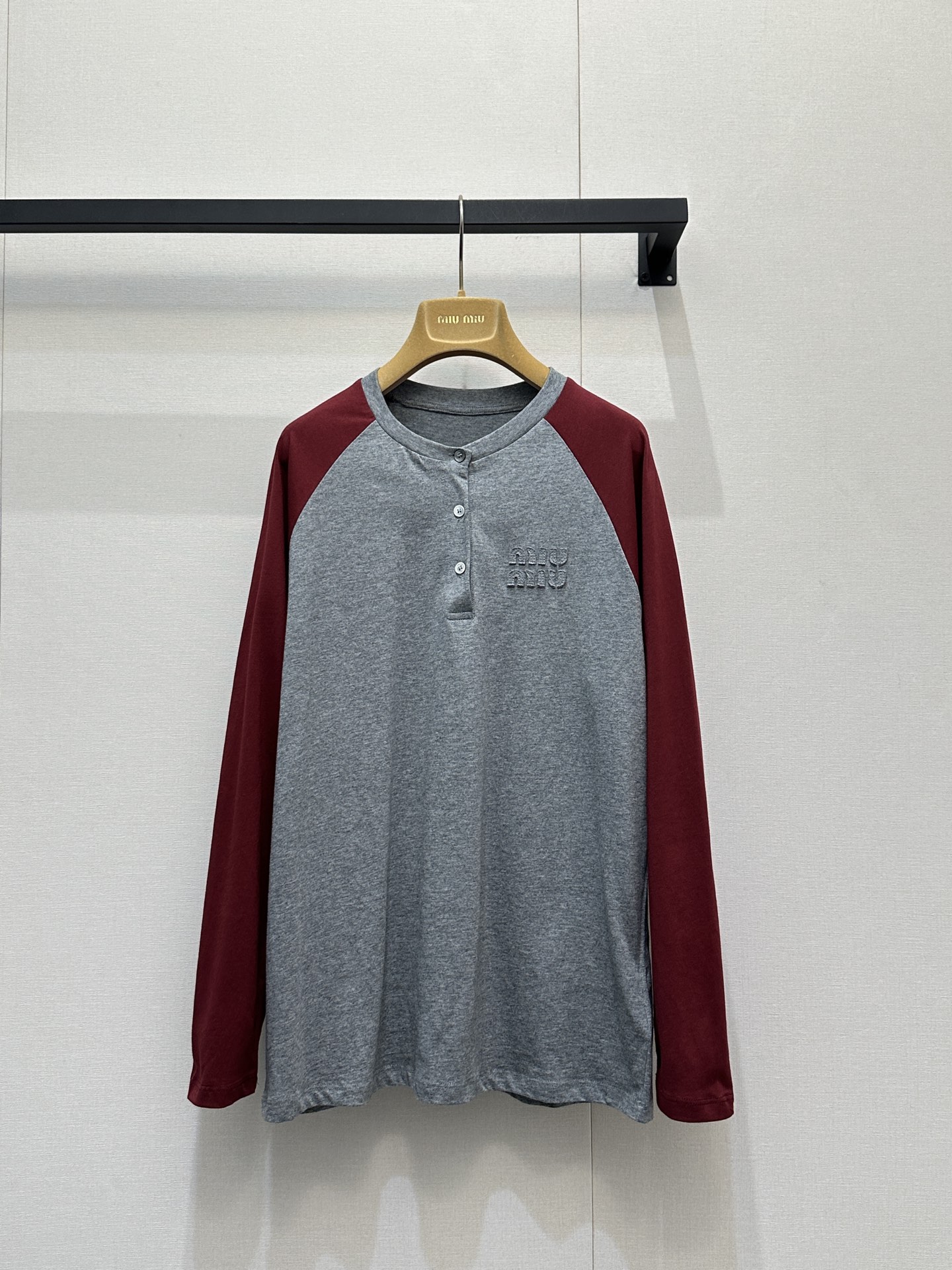 NO:735566,Miu M*u 26Ss early spring new style gray and red long-sleeved collar button T-shirt丨Exclusive high-end version!  Inspired by American retro baseball shirts, the classic raglan sleeve design is used to reshape the college style. The calm gray tones and warm red tones collide to create a vivid visual tension. The three-button detail on the neckline adds a sense of style. It can be opened to create a V-neck effect or buttoned to keep it neat. The three-dimensional appliqué logo on the chest is low-key for recognition, and the soft cotton blended fabric is comfortable.  Sturdy and crisp, the fit is tailored to fit the body shape but not tight. Pair it with a white work skirt for a sweet and cool girly style, and pair it with jeans for a casual and relaxed feel. It is a versatile item that can be worn layered or worn alone in early spring. S/M/L is now available for sale in large quantities, real shots, miumiu, skirts, jeans, tees, t-shirts,19860909Miu M*u 26Ss早春新款 灰红拼袖长袖领扣T恤丨独家高版出品！以美式复古棒球衫为灵感,用经典插肩袖设计重塑学院风.沉稳灰调与热烈红调碰撞出鲜活的视觉张力,领口三颗纽扣细节增添了造型感,可敞开打造V领效果,也可扣合保持利落.胸前立体贴布绣Logo低调彰显辨识度,柔软的棉混纺面料兼具舒适度与挺括感,合身剪裁贴合身形却不紧绷.搭配白色工装裙是甜酷少女风,配牛仔裤又能穿出随性松弛感,是早春叠穿与单穿都出彩的百搭单品.现货发售S/M/L大货实拍,,miumiu,skirts,jeans,tees，t-shirt,,Women's clothing