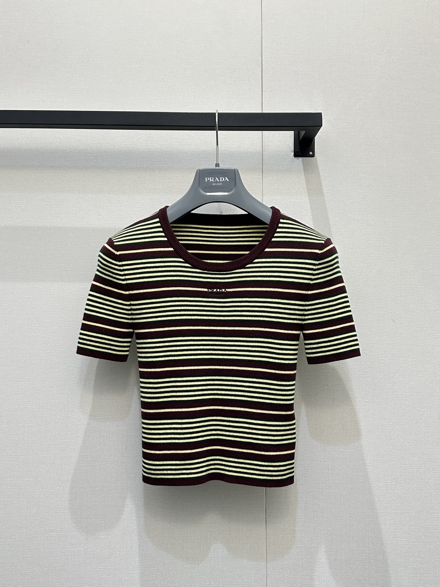 NO:792148,Prad*26's new classic striped knitted short-sleeve is also the brand's iconic retro commuter item. It is interwoven with three-color pinstripes of burgundy + mustard yellow + dark green, which is retro and high-end. It has a strong retro college atmosphere. It adopts a ribbed round neck design with ribbed cuffs and hem of the same color. It is neat and slim, fitting the body shape without losing comfort. The 'PRADA' letter logo is embroidered on the chest, low-key highlighting the brand identity. It is Prad  da’s classic identification symbol, slim and short tailoring with fine pitted knitted material, stretchy and skin-friendly, with both a crisp and drapey feel, suitable for spring and summer seasons, and a style that combines retro commuter style and intellectual feel. It is a representative item of Prada’s “old money style” wear. It can be paired with high-waisted suit pants, pleated skirts or denim skirts, with suits, windbreakers or knitted cardigans, and paired with loafers, tote bags or metal necklaces to enhance the sense of sophisticated commuting.  Size S M L large goods real shot, prada, loafers, totes, skirts, T-shirt, business suit, necklace,19860909Prad*26新款经典条纹针织短袖,也是品牌标志性的复古通勤单品,它以酒红+芥末黄+墨绿三色细条纹交织,复古又高级,自带浓郁的复古学院氛围,采用罗纹圆领设计,搭配同色系罗纹袖口与下摆,利落修身,贴合身形又不失舒适感,胸口位置绣有“PRADA”字母徽标,低调彰显品牌身份,是Prada的经典识别符号,修身短款剪裁搭配细腻坑条针织材质,弹力亲肤,兼具挺括感与垂坠感,适配春夏季节,风格上融合复古通勤风与知识分子感,是Prada“老钱风”穿搭的代表单品,可搭配高腰西装裤、百褶裙或牛仔半裙,外搭西装、风衣或针织开衫,再配上乐福鞋、托特包或金属项链,强化精致通勤感 码数S M L大货实拍,,prada,loafers,totes,skirts,T-shirt,business suit,necklace,,Women's clothing