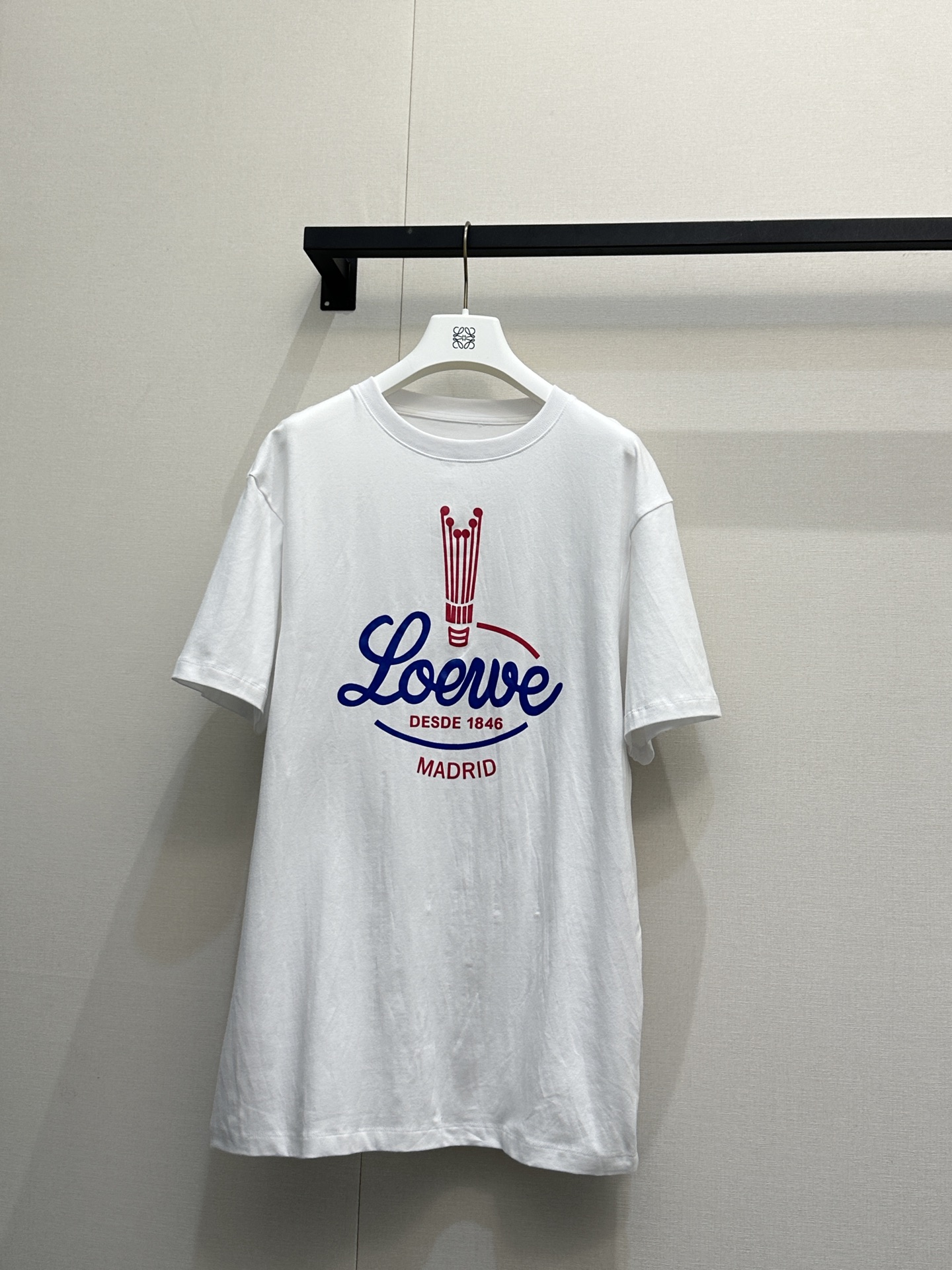 NO:795664,Loew*26's new retro distressed printed short-sleeved T-shirt, available in black and white, belongs to the brand's retro sports style series. It is made of loose shoulder design and soft and skin-friendly pure cotton fabric. The hem has a drawstring pleat design and the length can be adjusted to create a casual silhouette. The brand's iconic red and blue contrasting retro font 'Loewe' is printed on the front, paired with a red bottle-shaped pattern and 'DESDE 1846  The word 'MADRID' restores the retro atmosphere of the brand's origins in the 19th century. It has both a sense of casualness and high-level recognition, and is suitable for daily street or light retro wear styles. Size S M L. Real shot of large quantities, loewe, T-shirt, tees, t-shirt,19860909Loew*26新款的复古做旧印花短袖T恤,有黑白双色可选,属于品牌复古运动风系列.它采用宽松落肩版型与柔软亲肤的纯棉面料,下摆做抽绳收褶设计,可调节衣长营造随性廓形,正面印有品牌标志性的红蓝撞色复古字体“Loewe”,搭配红色瓶状图案与“DESDE 1846 MADRID”字样,还原19世纪品牌起源的复古氛围,兼具休闲感与高级辨识度,适配日常街头或轻复古穿搭风格. 码数S M L大货实拍,,loewe,T-shirt,tees，t-shirt,,Women's clothing