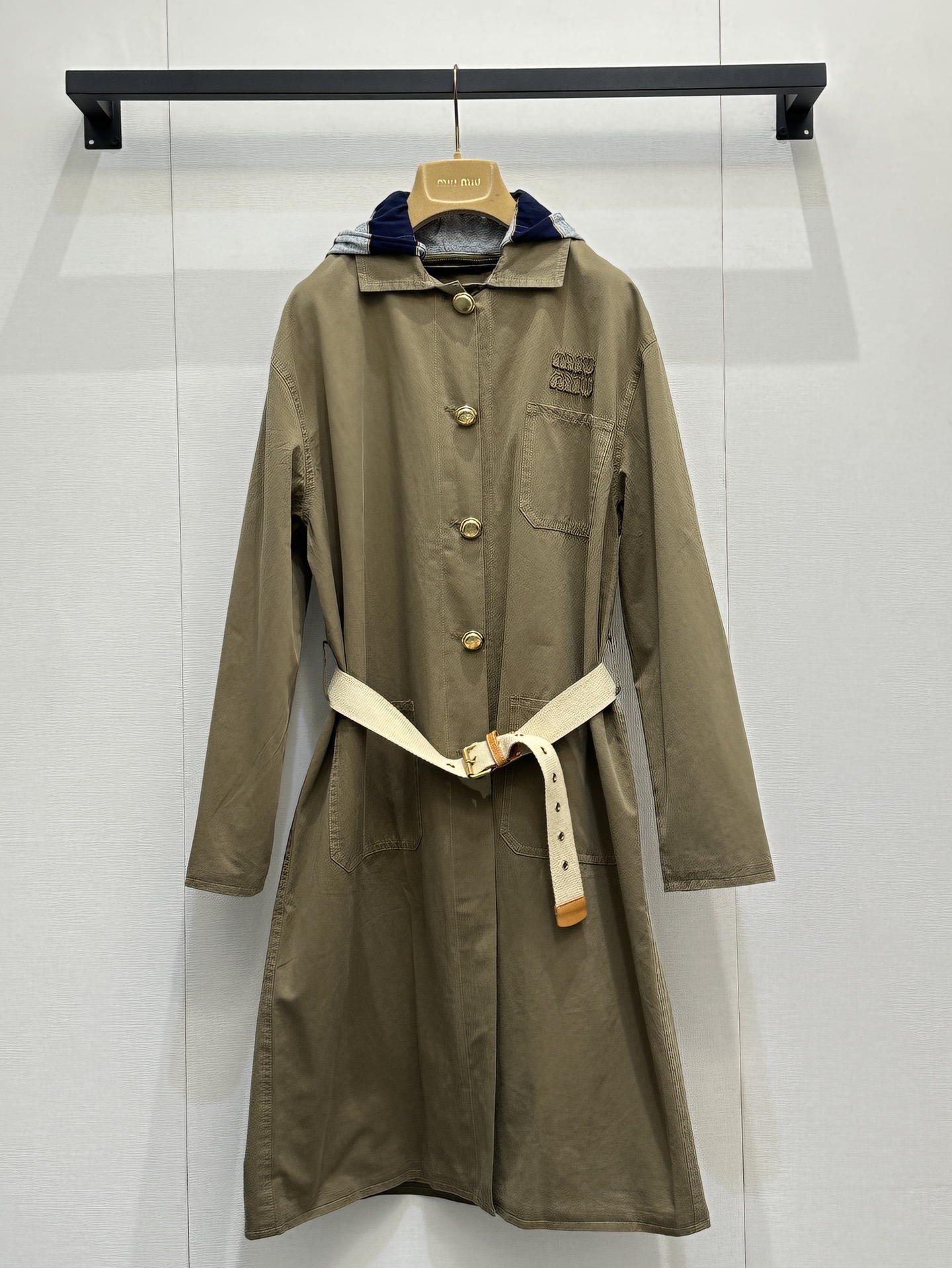 NO:796106,miu  mi*26's new khaki belted windbreaker has a relaxed retro workwear style. The lapels and golden breast buttons are neat and noble. The detachable hood design combines practicality and style. The same color belt tightens the waist to instantly optimize the proportion. The three-dimensional logo on the chest low-key highlights the brand recognition. The loose shoulders are dropped.  The cut is not flattering on the figure, and the mid-length length just covers the crotch line. It can be easily worn with jeans or skirts on a daily basis to give a casual and high-end feel. It is a versatile and attractive item with a sense of atmosphere in the spring and autumn wardrobe. Real photos of large quantities, miumiu, skirts, jeans, hats,19860909miu mi*26新款卡其色腰带风衣,自带松弛感的复古工装风,翻领+金色排扣利落又显贵,可拆卸连帽设计兼顾实用与造型感,同色系腰带收腰瞬间优化比例,胸前立体logo低调彰显品牌辨识度,宽松落肩剪裁不挑身材,中长款长度刚好遮住胯部线条,日常搭配牛仔裤或半裙都能轻松穿出随性高级感,是春秋季衣橱里百搭又耐看的氛围感单品.大货实拍,,miumiu,skirts,jeans,hats,,Women's clothing
