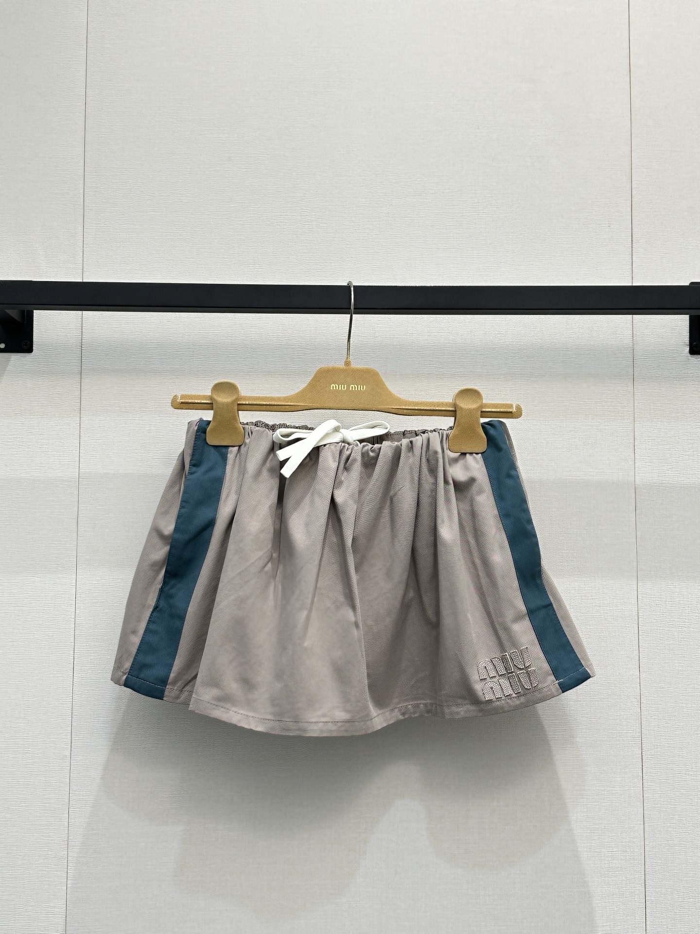 NO:796677,(Skirt) Miu Mi*26’s new retro sports style suit perfectly combines the 90s sports casual style with the brand’s iconic girly feel. The khaki main body is paired with dark green side stripes. The stand-up collar zipper jacket adopts raglan sleeves, ribbed stand-up collar and hem design, and the front full zipper is matched with three-dimensional Miu embossed on the chest.  The Miu logo and the same-color drawstring mini skirt are presented with elastic drawstrings at the waist and a flared A-line version. The hem is also embossed with a three-dimensional logo. Both are made of washed twill cotton fabrics with a distressed texture. They can be worn as a complete set to create a girly look, or they can be worn separately.  Suitable for more scenes, it is a popular item in the 2026 early spring series with both retro atmosphere and exquisite recognition, which perfectly interprets the 'miu in miu style' style. Actual shots of large quantities, miumiu, skirts, jackets  & coats,19860909（裙） Miu Mi*26新款复古运动风套装,将90年代运动休闲风格与品牌标志性少女感完美融合,卡其色主体搭配深绿色侧条纹,立领拉链夹克采用插肩袖、罗纹立领与下摆设计,正面全拉链搭配胸前压印立体Miu Miu徽标,同色系抽绳迷你短裙则以腰部弹力抽绳、喇叭A字版型呈现,下摆同样压印立体徽标,两者均采用水洗斜纹棉面料,自带做旧质感,既可以整套穿着打造元气少女感,也能拆分搭配适配更多场景,是2026早春系列中兼具复古氛围与精致辨识度的热门单品,完美诠释了“miu里miu气”的穿搭风格.大货实拍,,miumiu,skirts,jackets & coats,,Women's clothing