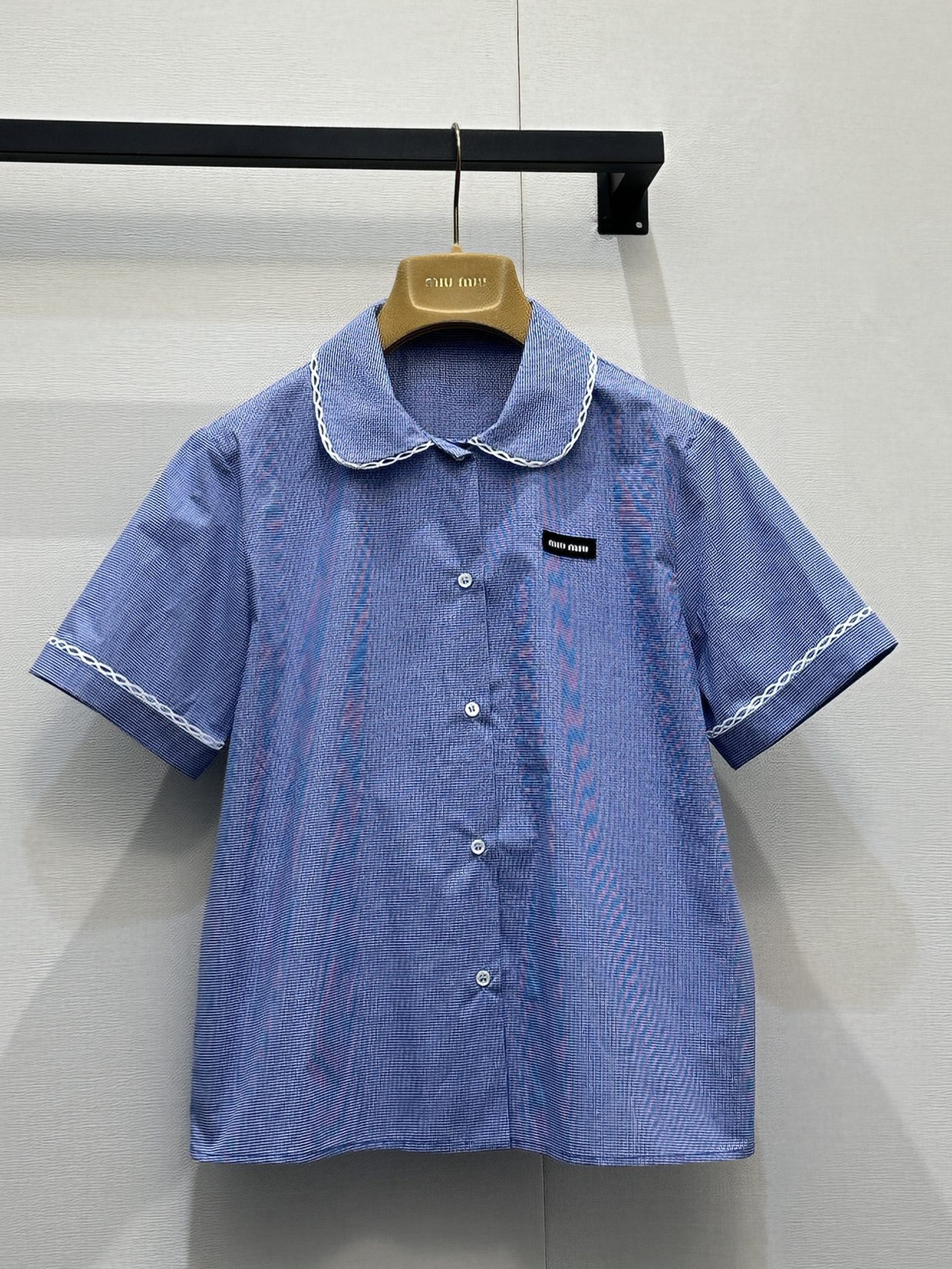 NO:802129,(Shirt) Miu Mi*26 new small plaid fresh girly style suit. It is made of light blue fine plaid cotton blended fabric with white lace. The suspender tube top is designed with thin shoulder straps and side bow ties. It has a loose A-line shape. The hem and the edge of the collar are decorated with white lace, and the hem is sewn with black Miu  Miu woven label; the short-sleeved lapel shirt of the same fabric is presented with a Peter Pan doll collar + single-row button placket. The cuffs and collar are also decorated with white lace, and a black Miu Miu woven label is sewn on the left chest. The overall texture is unified, which perfectly interprets the brand's iconic sweetness and retro atmosphere. Size S M L, real shot of large goods,, miumiu, shirts, T-shirt,19860909（衬衫） Miu Mi*26新款小格子清新少女风套装 以浅蓝细格纹棉质混纺面料搭配白色蕾丝花边,吊带抹胸上衣采用细肩带+侧部蝴蝶结系带设计,宽松A字版型,下摆与领口边缘饰有白色蕾丝花边,下摆处缝有黑色Miu Miu织标；同面料短袖翻领衬衫则以彼得潘娃娃领+单排纽扣门襟呈现,袖口与领口同样饰有白色蕾丝花边,左胸位置缝有黑色Miu Miu织标,整体质感统一,完美诠释了品牌标志性的甜美元气与复古氛围.码数S M L大货实拍,,miumiu,shirts,T-shirt,,Women's clothing