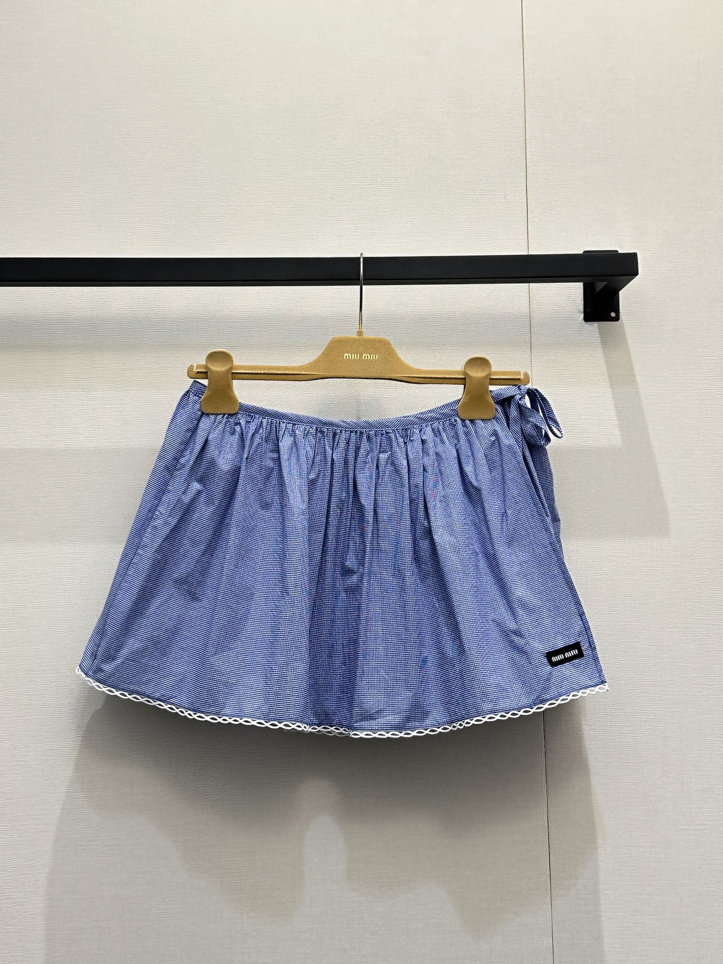 NO:802135,(Short skirt) Miu Mi*26 new small plaid fresh girly style suit. It is made of light blue fine plaid cotton blended fabric with white lace. The suspender tube top is designed with thin shoulder straps and side bow ties. It has a loose A-line version. The hem and the edge of the neckline are decorated with white lace, and the hem is sewn with black Miu  Miu woven label; the short-sleeved lapel shirt of the same fabric is presented with a Peter Pan doll collar + single-row button placket. The cuffs and collar are also decorated with white lace, and a black Miu Miu woven label is sewn on the left chest. The overall texture is unified, which perfectly interprets the brand's iconic sweetness and retro atmosphere. The size is S M L. Actual shot of large goods,, miumiu, skirts, shirts, T-shirt,19860909（短裙） Miu Mi*26新款小格子清新少女风套装 以浅蓝细格纹棉质混纺面料搭配白色蕾丝花边,吊带抹胸上衣采用细肩带+侧部蝴蝶结系带设计,宽松A字版型,下摆与领口边缘饰有白色蕾丝花边,下摆处缝有黑色Miu Miu织标；同面料短袖翻领衬衫则以彼得潘娃娃领+单排纽扣门襟呈现,袖口与领口同样饰有白色蕾丝花边,左胸位置缝有黑色Miu Miu织标,整体质感统一,完美诠释了品牌标志性的甜美元气与复古氛围.码数S M L大货实拍,,miumiu,skirts,shirts,T-shirt,,Women's clothing