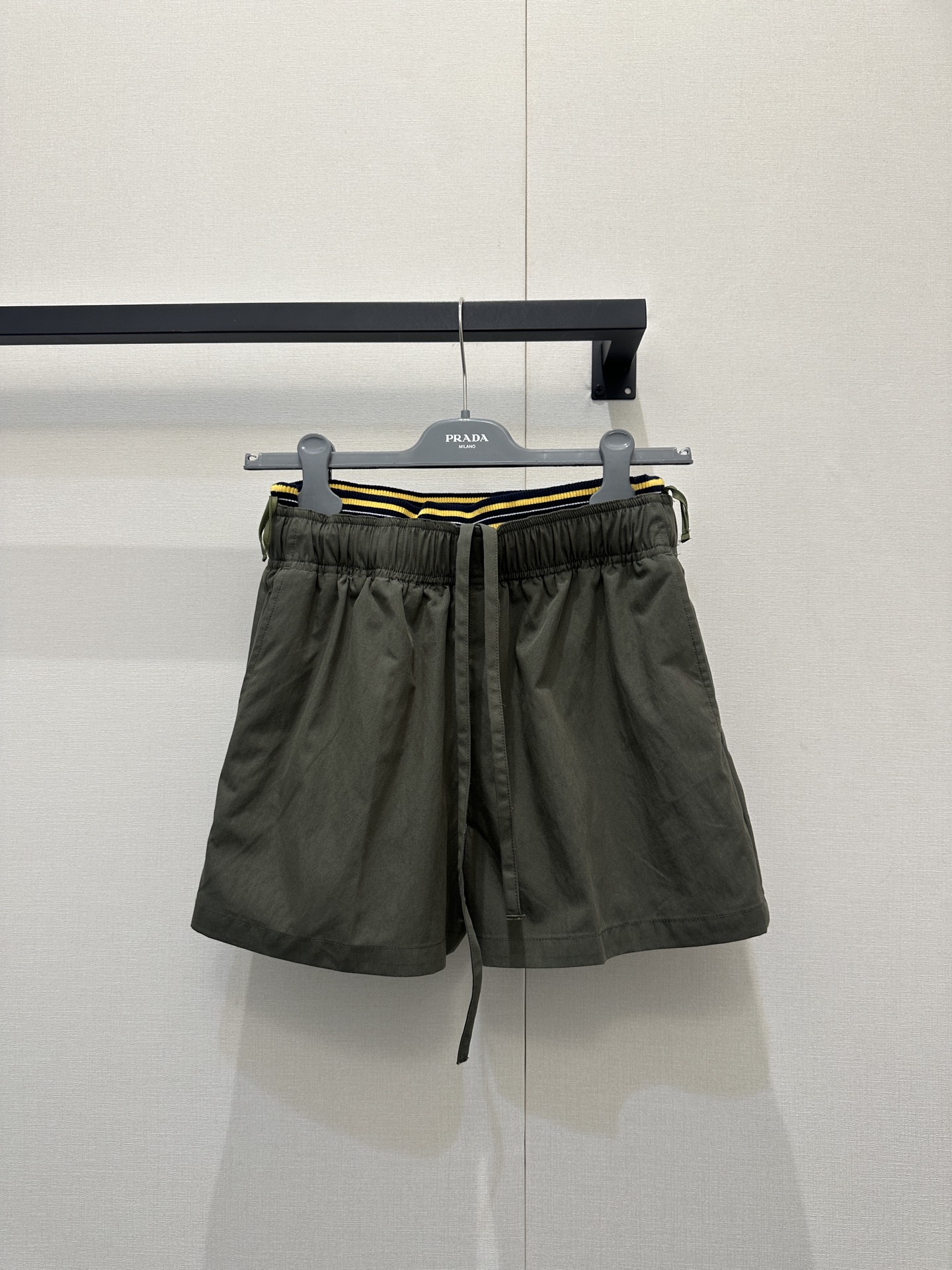 NO:806090,Prad*26's new olive green casual shorts turn sports style into a high-end formula. When the frankness of work pockets meets the vitality of contrasting waistbands, these Prada shorts have become the 'style cheat' of the summer wardrobe - the neat A-line version hides the flesh and shows the length of the legs. The large pockets on both sides and the triangle logo are embellished with a cool workwear feel. The black and yellow striped waist instantly brightens the look; it is made of crisp and thin fabric, drape, breathable, and passable.  Suitable for shopping and vacation. You can wear it with a short jacket from the same brand for a street cool look, an off-white T-shirt for a simple and high-end look, or even pair it with dad shoes and piles of socks for a casual college style, making you synonymous with 'casual yet sophisticated' in summer. The cargo pockets can hold the trivial things of life, and are full of Prada's fashion confidence. Size SML, real shots, prada, shorts, jackets  & coats,tees,t-shirt,19860909Prad*26新款橄榄绿休闲短裤把运动风穿成高级感公式当工装口袋的率性撞上撞色腰头的活力,这条Prada短裤便成了夏日衣橱的“风格作弊器”——利落A字版型藏肉显腿长,双侧大口袋与三角徽标点缀工装酷飒感,黑黄条纹腰头瞬间点亮造型；采用挺括轻薄面料,垂坠透气,通勤逛街度假皆宜.可搭同品牌短款外套演绎街头潮酷,配米白T恤诠释简约高级,甚至配老爹鞋与堆堆袜穿出休闲学院风,让你成为夏日里“随性又精致”的代名词,工装口袋装得下生活琐碎,亦盛满Prada的时尚底气.尺码SML大货实拍,,prada,shorts,jackets & coats,tees，t-shirt,,Women's clothing