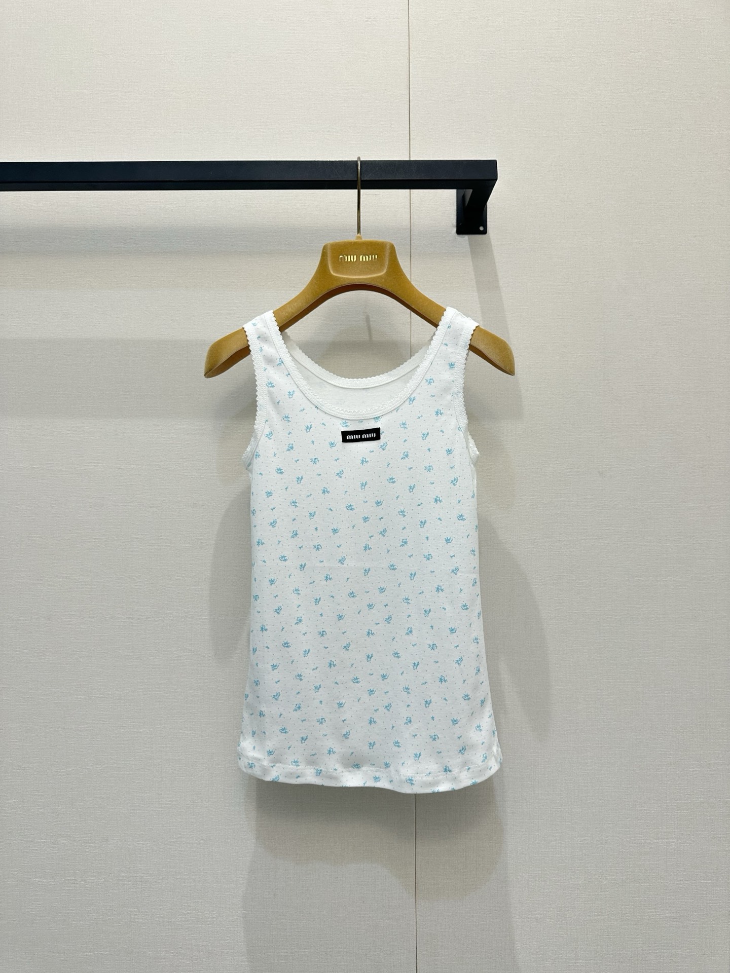 NO:840086,(Vest) Mium*u 26Fw early spring new style micro-label floral print T-shirt丨Exclusive high-end version!  Made of soft and skin-friendly knitted fabric, it has micro-elastic properties and fits the body shape without being tight. The white background is covered with mini floral prints, and the neckline is embellished with the iconic black micro-label webbing. The sweet elements are integrated with minimalist luxury brand recognition. The slim-fitting micro-elastic tailoring can outline the body curve without being too cramped. It is compatible with various body types and can be easily controlled for daily commuting and dating. Ready for sale S/M/L, miumiu, tees, t-shirt,19860909（背心）Mium*u 26Fw早春新款 微标碎花印花T恤丨独家高版出品！选用软糯亲肤的针织面料,自带微弹属性,贴合身形却不紧绷,白底铺陈迷你碎花印花,领口处点缀标志性黑色微标织带,甜美元素里融入极简奢牌辨识度,修身微弹剪裁,既能勾勒身形曲线,又不会过于局促,兼容各种身型,日常通勤、约会出街都能轻松驾驭.现货发售S/M/L,,miumiu,tees，t-shirt,,Women's clothing