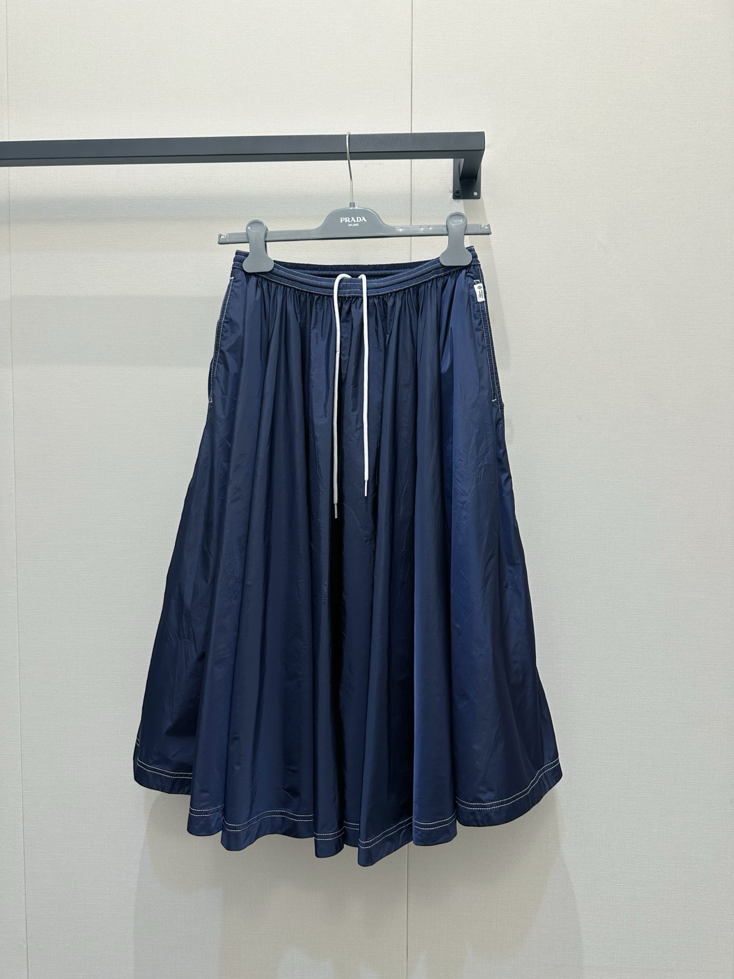 NO:842333,Prada Re-Nylon regenerated nylon A-line skirt | When environmentalism meets Italian elegance. This regenerated nylon skirt is made from recycled ocean plastic, turning Prada's sustainable fashion concept into a walking work of art.  The iconic dark blue tone is paired with a neat A-line silhouette. The contrasting drawstring at the waist not only modifies the waistline but also adds sporty vitality. The open stitching at the hem hides the exquisite craftsmanship of the Milan workshop. From commuting to dating, it allows you to have the pride of an environmental pioneer and the dignity of Italian luxury goods in comfortable and crisp recycled fabrics.  Hidden side pockets + original hangers + the same washable label at the counter, every detail tells that this is no ordinary skirt, it is a love letter written by Prada for the earth using technology, prada, skirts,19860909Prada Re-Nylon再生尼龙A字半裙｜当环保主义遇上意式优雅这件采用海洋回收塑料再造的再生尼龙半裙,把Prada的可持续时尚理念穿成了行走的艺术品 标志性的深蓝色调搭配利落A字廓形,腰间撞色抽绳既修饰腰线又添运动活力,下摆明线走线藏着米兰工坊的精湛工艺.从通勤到约会,它都能让你在舒适挺括的再生面料里,同时拥有环保先锋的骄傲和意大利奢侈品的体面 侧边隐藏口袋+原厂衣架+专柜同款水洗标,每个细节都在诉说这不是普通的半裙,是Prada用科技为地球写的情书,,prada,skirts,,Women's clothing