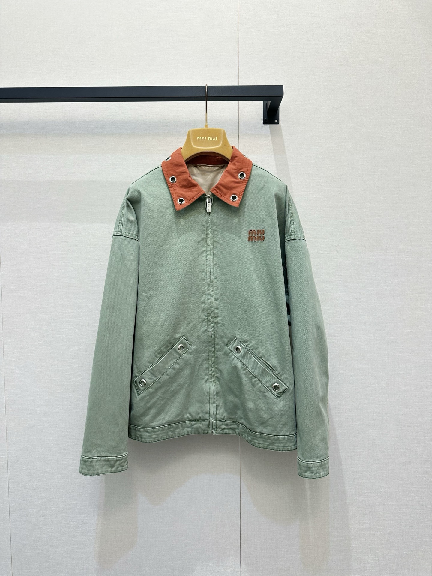 NO:843850,Miu Miu 26 spring and summer show new retro denim jacket. This gray-green jacket is highlighted by an unexpected orange metal collar. The coldness and fierceness collide at the collar, instantly breaking the dullness. It is worn with a blue and white floral T-shirt, with tiny flowers looming, injecting a touch of pastoral poetry into the whole. A spring and summer show denim apron is layered around the waist. The multi-pocket design and details transform workwear pragmatism into playful decoration, with a perfect sense of layering.  Every step brings an uninhibited fashionable attitude. Spot SML,,miumiu,skirts,jackets & coats,jackets & coats,tees,t-shirt,19860909Miu Miu 26春夏秀场新品复古牛仔外套 这件灰绿色夹克以出人意料的橘色金属领子点睛,冷冽与炽烈在领口碰撞,瞬间打破沉闷.内搭蓝白碎花T恤,细碎花朵若隐若现,为整体注入一丝田园诗意.腰间叠穿春夏秀款牛仔围裙,多口袋设计与细节,将工装实用主义转化为俏皮装饰,层次感满分 每一步都带着不羁的时髦态度现货SML,,miumiu,skirts,jackets & coats,jackets & coats,tees，t-shirt,,Women's clothing