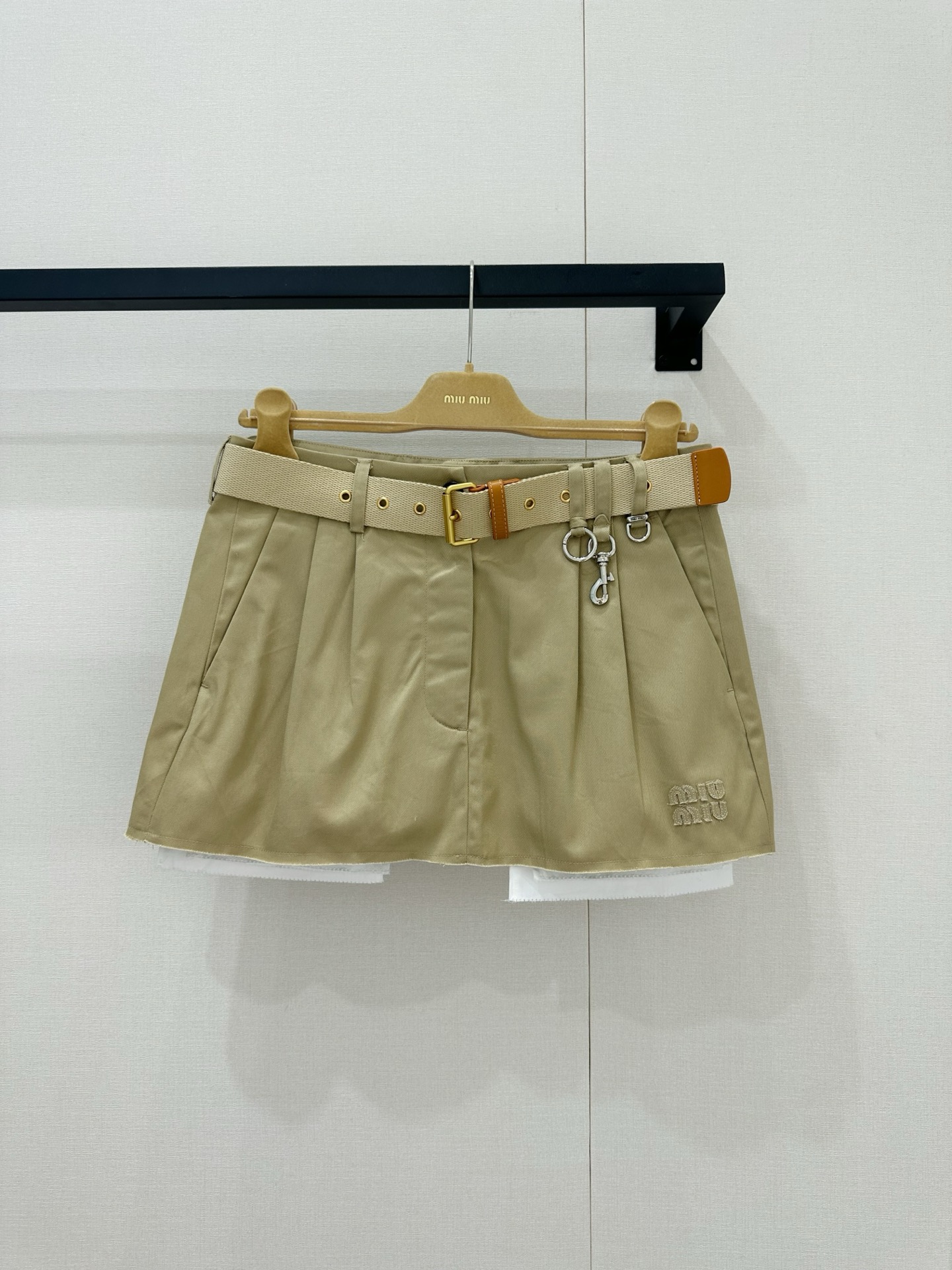 NO:870745,Miu Miu 26’s latest khaki skirt really brings out the “college girl look”!  This classic pleated version comes with an age-reducing filter, but Miu  Miu chose to add a metal buckle to the waist, instantly injecting a sweet and cool punk atmosphere, and perfectly grasping the contradiction between rebellious and well-behaved. The most unique thing is its double-layer design. The crisp khaki fabric on the outer layer is paired with the white tulle/shorts splicing on the inner layer, which not only enriches the visual hierarchy, but also cleverly increases the practicality of preventing light leakage. The white edges that are vaguely exposed when walking are as light and flexible as clouds. The corners of the skirt are low.  The colorful logo embroidery is the kind of high-end code that people who know it naturally understand. Paired with the dark brown striped sweater just now, it is a perfect early autumn retro suit; worn alone with a white T-shirt or small leather shoes, it also looks like a fresh and bright Y2K girl. This skirt really balances fashion and practicality just right~,,miumiu,skirts,shorts,tees,t-shirt,19860909Miu Miu 26最新款的这条卡其色半裙真的把“学院少女感”玩出花了！ 这种经典的百褶版型自带减龄滤镜,但Miu Miu偏偏要在腰侧加上金属扣环的设计,瞬间注入了甜酷的朋克气息,把那种叛逆又乖巧的矛盾感拿捏得死死的.最绝的是它的双层设计,外层挺括的卡其色面料搭配内层的白色薄纱/短裤拼接,不仅丰富了视觉层次,还巧妙地增加了防走光的实用性,走动间隐约露出的白边,像云朵一样轻盈灵动.裙摆角落低调的Logo刺绣,是那种懂的人自然懂的高级暗号.搭配刚才那件深棕色条纹针织衫,简直就是完美的早秋复古套装；单穿配个白T恤或小皮鞋,又是一番清新明亮的Y2K少女模样,这条裙子真的是把时髦和实穿平衡得刚刚好～,,miumiu,skirts,shorts,tees，t-shirt,,Women's clothing