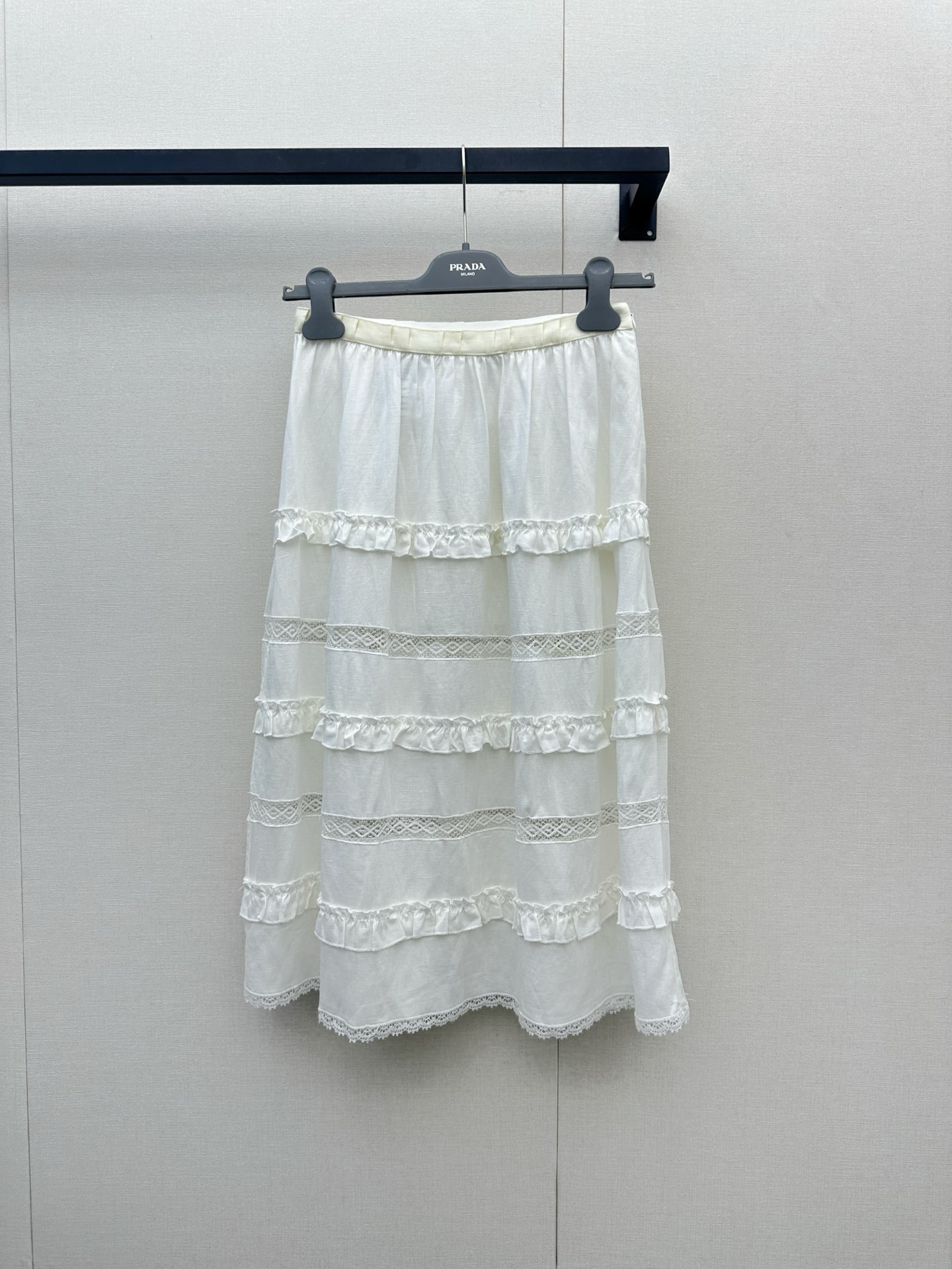 NO:878092,Prada 26 spring and summer new cotton linen skirt  The natural and breathable blended fabric brings you a refreshing and pleasant summer wearing experience. The light texture seems to apply a layer of cool mint to the skin, which perfectly dissipates the sultry heat. Under the pure off-white tone, the complex texture is looming under the light and shadow, giving the item a low-key artistic texture and full of three-dimensional layers. It is supplemented by a playful spaghetti strap design and a wavy lace hem.  , not only outlines the soft shoulder and neck lines, but also reveals a trace of lazy French style in the breeze. Whether worn as a layered suit jacket, or worn alone with high-waisted jeans or a pleated skirt, it can easily deduce a refreshing and refined, high-end yet girly summer fashion attitude.,,prada,skirts,jeans,jackets  & coats, business suits,19860909Prada 26春夏新款棉质亚麻半裙 以天然透气的混纺面料为你带来清爽宜人的夏日穿着体验,轻盈的质地仿佛给肌肤敷上一层微凉的薄荷,完美驱散闷热；纯净的米白色调下,繁复的纹理在光影下若隐若现,赋予单品低调的艺术质感与满满的立体层次；辅以俏皮的细肩带设计与波浪形的蕾丝花边下摆,不仅勾勒出柔美的肩颈线条,更在微风中透出一丝慵懒的法式风情,无论是作为内搭叠穿西装外套,还是单穿搭配高腰牛仔裤或百褶裙,都能轻松演绎出清爽脱俗、高级又不失少女感的夏日时尚态度.,,prada,skirts,jeans,jackets & coats,business suit,,Women's clothing