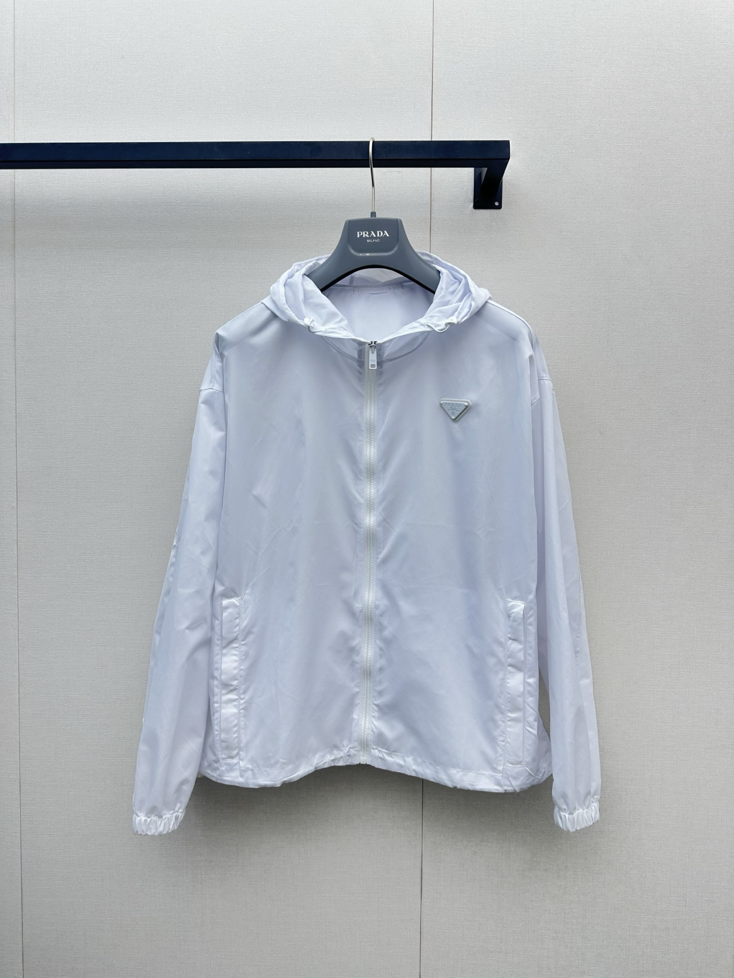 NO:878095,Pra** classic triangle logo hooded sun protection jacket. The pure white tone has a refreshing and high-end feel. The iconic triangle logo low-key highlights the brand style. Lightweight and breathable windproof fabric, with both sun protection and practical functions, no burden for summer travel. Loose hooded version, neat tailoring does not flatter the figure, easy to create casual and high-end street wear. Ready for sale smL, prada, hats,19860909Pra**经典三角标连帽防晒衣 纯净白调自带清爽高级感,标志性三角徽标低调彰显品牌格调 轻薄透气的防风面料,兼具防晒与实用功能,夏日出行无负担 宽松连帽版型,利落剪裁不挑身材,轻松打造随性高级的街头穿搭现货出售smL,,prada,hats,,Women's clothing