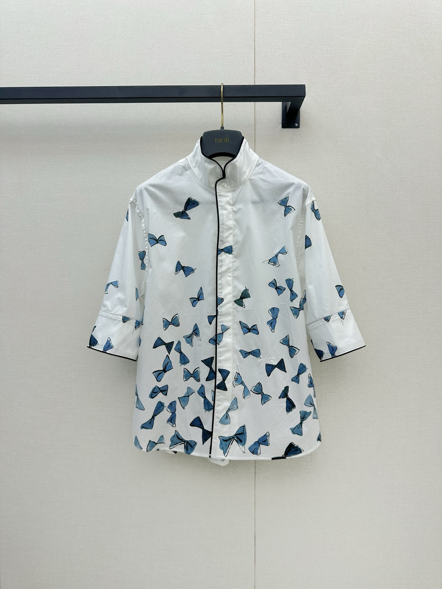 NO:878659,Dior 2026 new blue bow print short-sleeved shirt, white base fabric with blue bow print, fresh and elegant, with a spring and summer atmosphere. Lightweight cotton fabric, comfortable and breathable to wear, black piping details enhance the sense of hierarchy. Short sleeves + stand-up collar design, can be easily worn in daily life or vacation, looks great with skirts or casual pants, feminine and fashionable!  ,,dior,skirts,shirts,T-shirt,19860909Dior 2026新款蓝色蝴蝶结印花短袖衬衫,白色底布配蓝色蝴蝶结印花,清新优雅超有春夏氛围感.轻薄棉质面料,穿着舒适透气,黑色滚边细节提升层次感.短袖+立领设计,日常或度假都能轻松驾驭,搭配裙装或休闲裤都很出彩,柔美又时髦！,,dior,skirts,shirts,T-shirt,,Women's clothing