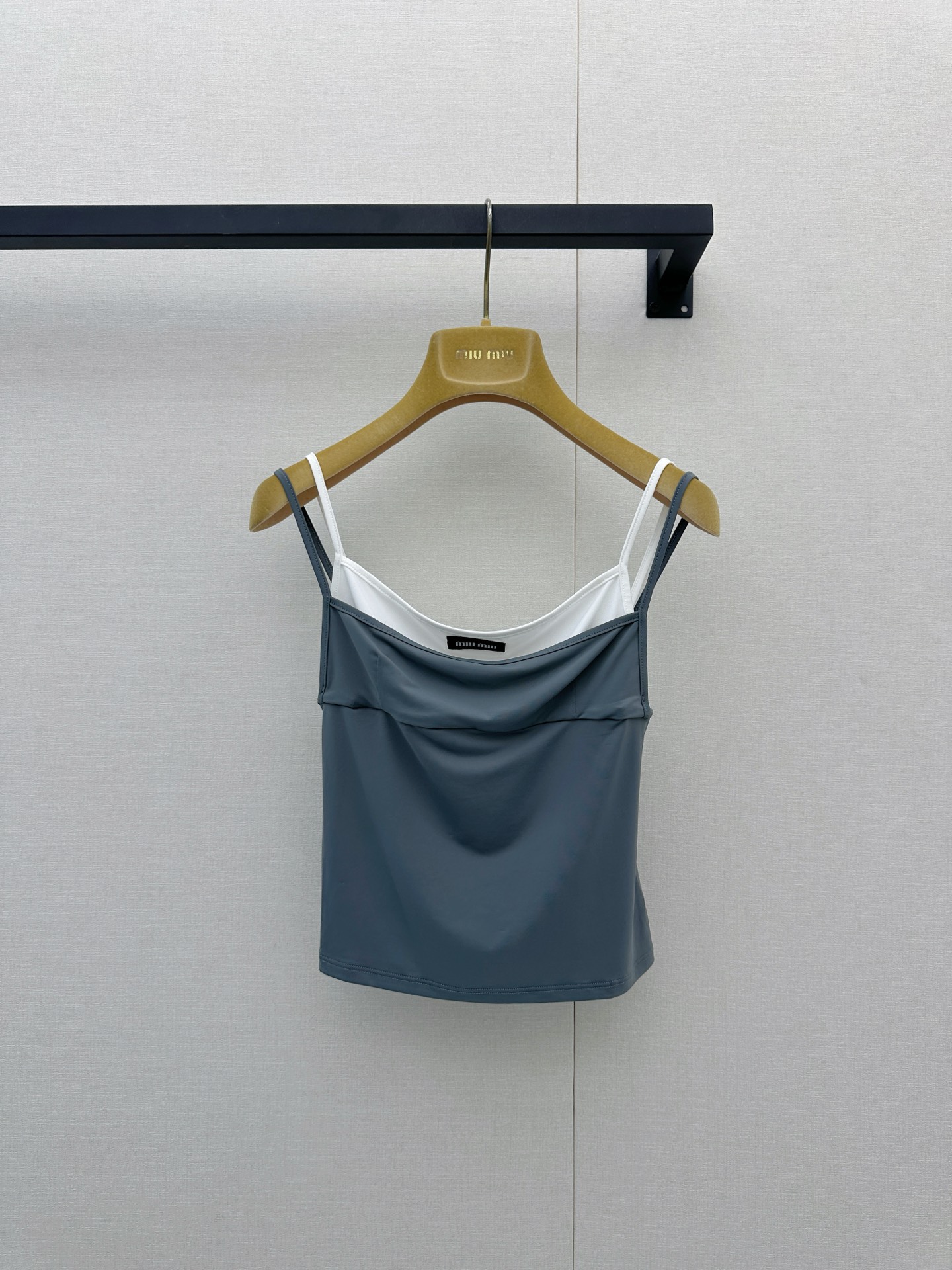 NO:907312,Miu Miu  26 new fake two-piece slings inject fresh vitality into the spring and summer wardrobe with a very ingenious stacking design. The outer slings in dark gray (or navy blue) are loose and hanging, and the inner white base is looming, creating a rich sense of layering and  It has a lazy and casual atmosphere, and you can easily show your fashionable attitude without having to worry about matching it. The spaghetti strap design modifies the shoulder and neck lines, and the slightly swaying neckline adds a bit of femininity and sexiness. It can be used as an inner layer with a suit or cardigan for commuting or leisure wear.  The casual style can also be worn alone with jeans or a skirt to release youthful vitality on sunny days. The small brand logo on the chest is a low-key finishing touch, retaining recognition while still being simple and high-end. It is a versatile tool that perfectly balances practicality and design, allowing you to casually interpret the freshness and playfulness of Miu girls on the urban streets. Real photos of large goods, miumiu, skirts, jeans, business  suit,19860909Miu Miu 26新款假两件吊带,以极具巧思的叠穿设计为春夏衣橱注入清新活力.深灰色（或藏青色）的外层吊带宽松垂坠,内层白色打底若隐若现,营造出丰富的层次感与慵懒随性的氛围,无需费心搭配便能轻松彰显时髦态度.细肩带设计修饰肩颈线条,微荡的领口更添几分柔美与小性感,既可作为内搭与西装、开衫组合打造通勤或休闲造型,也能单穿搭配牛仔裤或半裙,在阳光明媚的日子里释放青春活力.胸前小巧的品牌Logo低调点睛,保留辨识度的同时不失简约高级,是一件将实穿性与设计感完美平衡的百搭利器,让你在都市街头随性演绎属于Miu系女孩的清新与俏皮.大货实拍,,miumiu,skirts,jeans,business suit,,Women's clothing