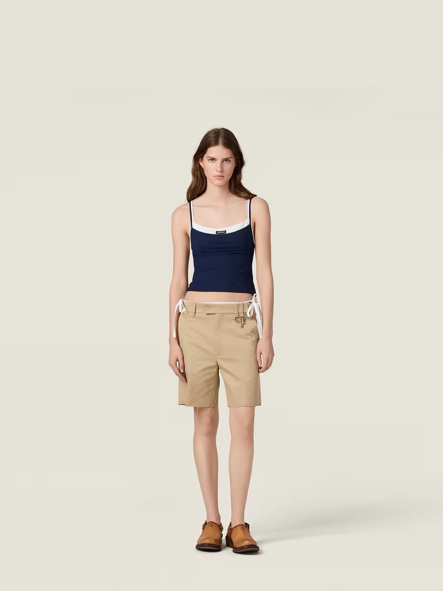 NO:907266,Miu Miu  26 new fake two-piece slings inject fresh vitality into the spring and summer wardrobe with a very clever stacking design. The dark gray (or navy) outer sling hangs loosely, and the inner white base is looming, creating a rich sense of layering  With a lazy and casual atmosphere, you can easily show your fashionable attitude without having to worry about matching. The spaghetti strap design modifies the shoulder and neck lines, and the slightly swaying neckline adds a bit of femininity and sexiness. It can be used as an inner layer with a suit or cardigan for commuting.  It can be worn casually or alone with jeans or a skirt to release youthful vitality on sunny days. The small brand logo on the chest is a low-key eye-catcher, retaining recognition while still being simple and high-end. It is a versatile tool that perfectly balances practicality and design, allowing you to casually interpret the freshness and playfulness of Miu girls on the urban streets.,,miumiu,skirts,jeans,business  suit,19860909Miu Miu 26新款假两件吊带,以极具巧思的叠穿设计为春夏衣橱注入清新活力.深灰色（或藏青色）的外层吊带宽松垂坠,内层白色打底若隐若现,营造出丰富的层次感与慵懒随性的氛围,无需费心搭配便能轻松彰显时髦态度.细肩带设计修饰肩颈线条,微荡的领口更添几分柔美与小性感,既可作为内搭与西装、开衫组合打造通勤或休闲造型,也能单穿搭配牛仔裤或半裙,在阳光明媚的日子里释放青春活力.胸前小巧的品牌Logo低调点睛,保留辨识度的同时不失简约高级,是一件将实穿性与设计感完美平衡的百搭利器,让你在都市街头随性演绎属于Miu系女孩的清新与俏皮.,,miumiu,skirts,jeans,business suit,,Women's clothing