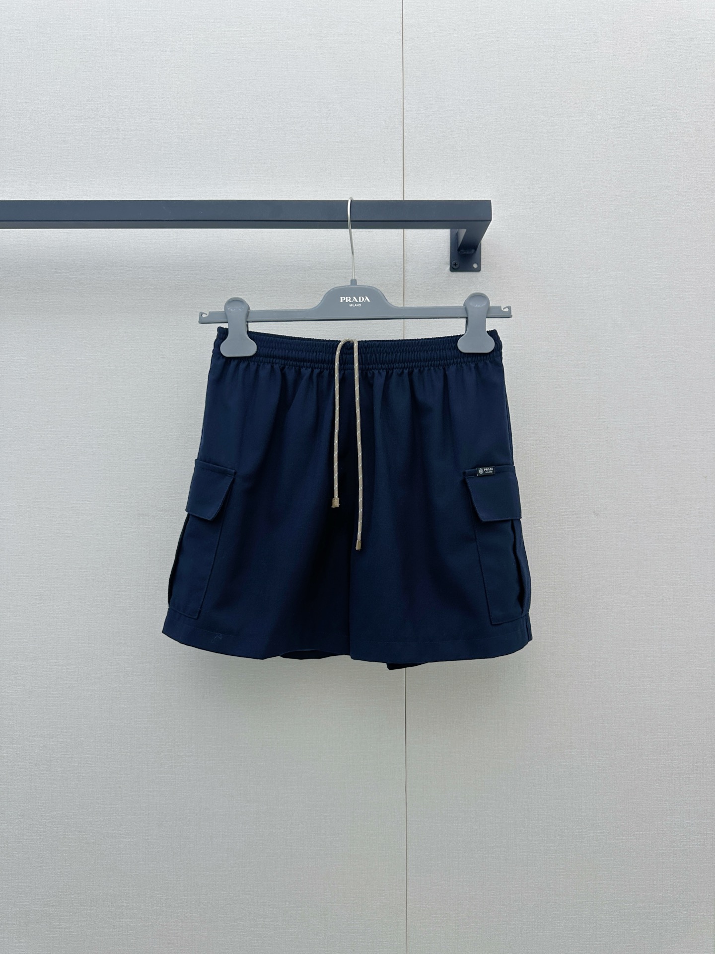 NO:911844,Prada  26 new black cargo shorts, reshape urban leisure aesthetics with a neat silhouette ~ elastic waistband with off-white contrasting drawstring (the rope body is embellished with brand iconic details), injecting a touch of softness into the coolness; large three-dimensional patch pockets on the front +  Hidden pockets on the sides combine practical functions with style. The small patch pockets on the back add exquisite details. The overall cut is loose and drapey, exuding a casual aura when walking. Selected 75 virgin sheep wool + 25 mohair blended fabrics, soft and waxy to the touch.  It is skin-friendly and has a slight stiffness. It is lined with regenerated cupro fiber, which is breathable, skin-friendly and environmentally friendly. It can be worn in all seasons with both texture and comfort. Whether it is paired with a regenerated nylon vest from the same series to create a modern suit, or paired with a simple white T or a knitted sweater to switch to daily casual style, it can be effortlessly fashionable, allowing you to firmly grasp the elegance and comfort of a Prada girl in the urban rhythm. Size SML is in stock, prada, shorts,19860909Prada 26新款黑色工装短裤,以利落廓形重塑都市休闲美学～松紧腰头搭配米白撞色抽绳（绳身缀有品牌标志性细节）,在酷感中注入一丝柔和辨识度；正面立体大贴袋+侧边隐藏口袋,兼具实用机能与造型层次,后侧小贴袋更添精致细节,整体剪裁宽松垂坠,行走间流露随性气场.甄选75初剪绵羊毛+25马海毛混纺面料,触感软糯亲肤且自带微挺括度,内里搭配再生铜氨纤维,透气亲肤又环保,四季穿搭皆能兼顾质感与舒适.无论是搭配同系列再生尼龙背心打造摩登套装,还是配简约白T、针织衫切换日常休闲风,它都能以毫不费力的时髦姿态,让你在都市节奏里,稳稳拿捏Prada女孩的优雅与自在.尺码SML大货实拍,,prada,shorts,,Women's clothing