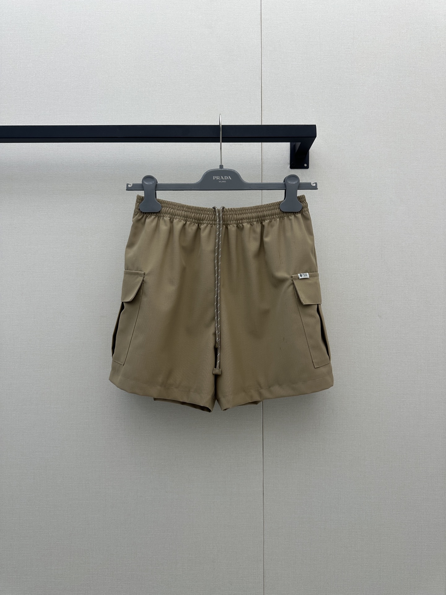 NO:911838,Prada  26 new khaki work shorts, reshaping urban leisure aesthetics with a neat silhouette ~ elastic waistband with off-white contrasting drawstring (the rope body is embellished with brand signature details), injecting a touch of softness into the coolness; large three-dimensional patch pockets on the front +  Hidden pockets on the sides combine practical functions with style. The small patch pockets on the back add exquisite details. The overall cut is loose and drapey, exuding a casual aura when walking. Selected 75 virgin sheep wool + 25 mohair blended fabrics, soft and waxy to the touch.  It is skin-friendly and has a slight stiffness. It is lined with regenerated cupro fiber, which is breathable, skin-friendly and environmentally friendly. It can be worn in all seasons with both texture and comfort. Whether it is paired with a regenerated nylon vest from the same series to create a modern suit, or paired with a simple white T or a knitted sweater to switch to daily casual style, it can be effortlessly fashionable, allowing you to firmly grasp the elegance and comfort of a Prada girl in the urban rhythm. Size SML is in stock, prada, shorts,19860909Prada 26新款卡其色工装短裤,以利落廓形重塑都市休闲美学～松紧腰头搭配米白撞色抽绳（绳身缀有品牌标志性细节）,在酷感中注入一丝柔和辨识度；正面立体大贴袋+侧边隐藏口袋,兼具实用机能与造型层次,后侧小贴袋更添精致细节,整体剪裁宽松垂坠,行走间流露随性气场.甄选75初剪绵羊毛+25马海毛混纺面料,触感软糯亲肤且自带微挺括度,内里搭配再生铜氨纤维,透气亲肤又环保,四季穿搭皆能兼顾质感与舒适.无论是搭配同系列再生尼龙背心打造摩登套装,还是配简约白T、针织衫切换日常休闲风,它都能以毫不费力的时髦姿态,让你在都市节奏里,稳稳拿捏Prada女孩的优雅与自在.尺码SML大货实拍,,prada,shorts,,Women's clothing