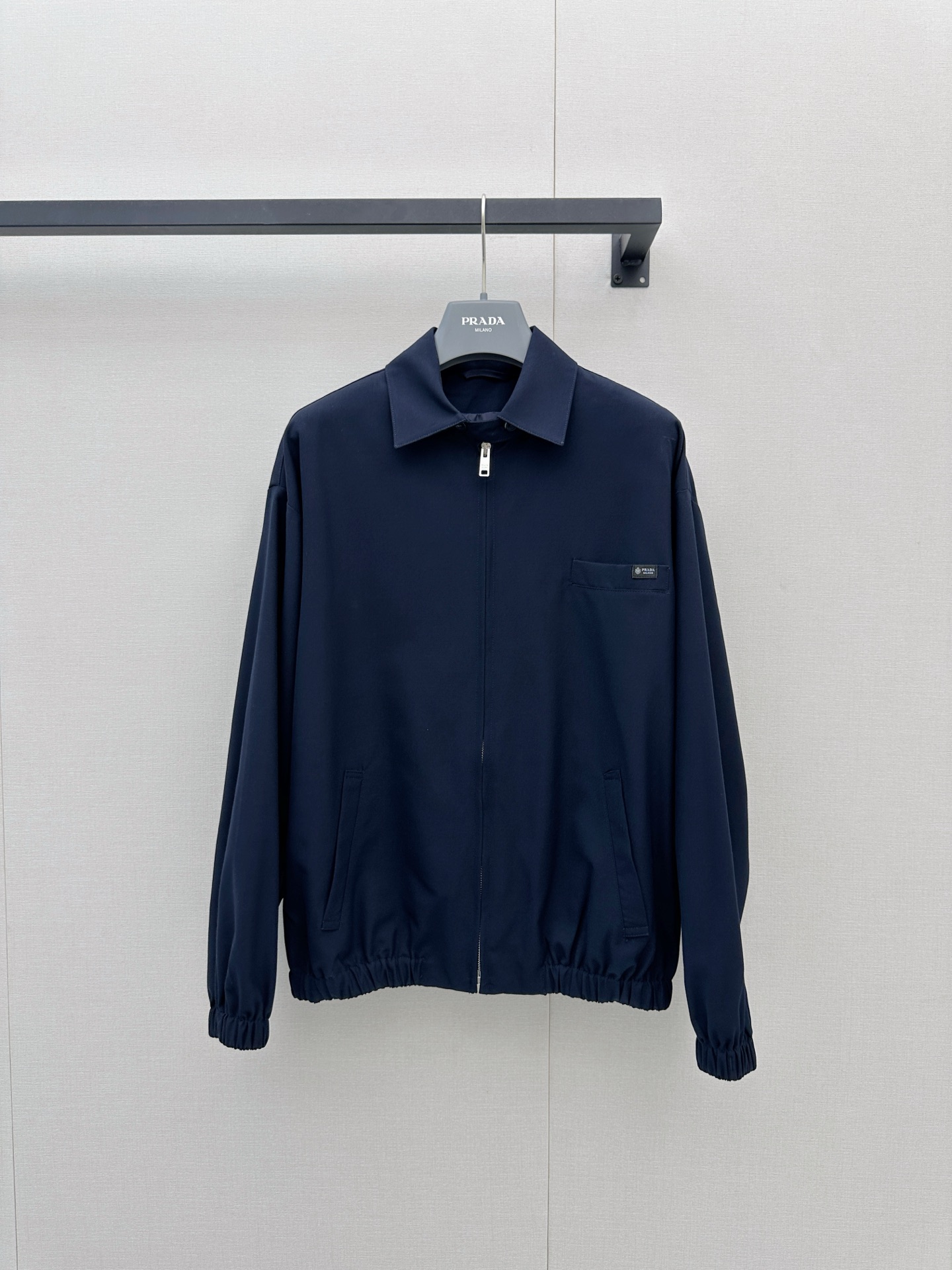 NO:924901,Prada wool jacket  It adopts a dark blue tone and a classic lapel zipper design, and the overall style is simple and modern. The jacket is equipped with a metal zipper on the front, a patch pocket with a brand logo on the left chest, and the hem and cuffs are designed with elastic cuffs, taking into account both comfort and style. This jacket belongs to the 2026 autumn and winter  This series is suitable for daily commuting or casual occasions. Its neat tailoring and crisp fabrics can well modify the body shape while maintaining freedom of movement. Dark blue is a versatile color and is easy to match with all kinds of inner wear and trousers. SML's actual photos of large products, prada, jackets  & coats,jackets & coats,19860909Prada羊毛夹克外套 采用深蓝色调与经典翻领拉链设计,整体风格简约而富有现代感.夹克正面配有金属拉链,左胸处设有带品牌标识的贴袋,下摆与袖口均采用松紧收口设计,兼顾舒适性与造型感.该款夹克属于2026秋冬系列,适合日常通勤或休闲场合穿着,其剪裁利落、面料挺括,能很好地修饰身形,同时保持活动自由度.深蓝色作为百搭色系,易于搭配各类内搭与裤装,SML大货实拍,,prada,jackets & coats,jackets & coats,,Women's clothing