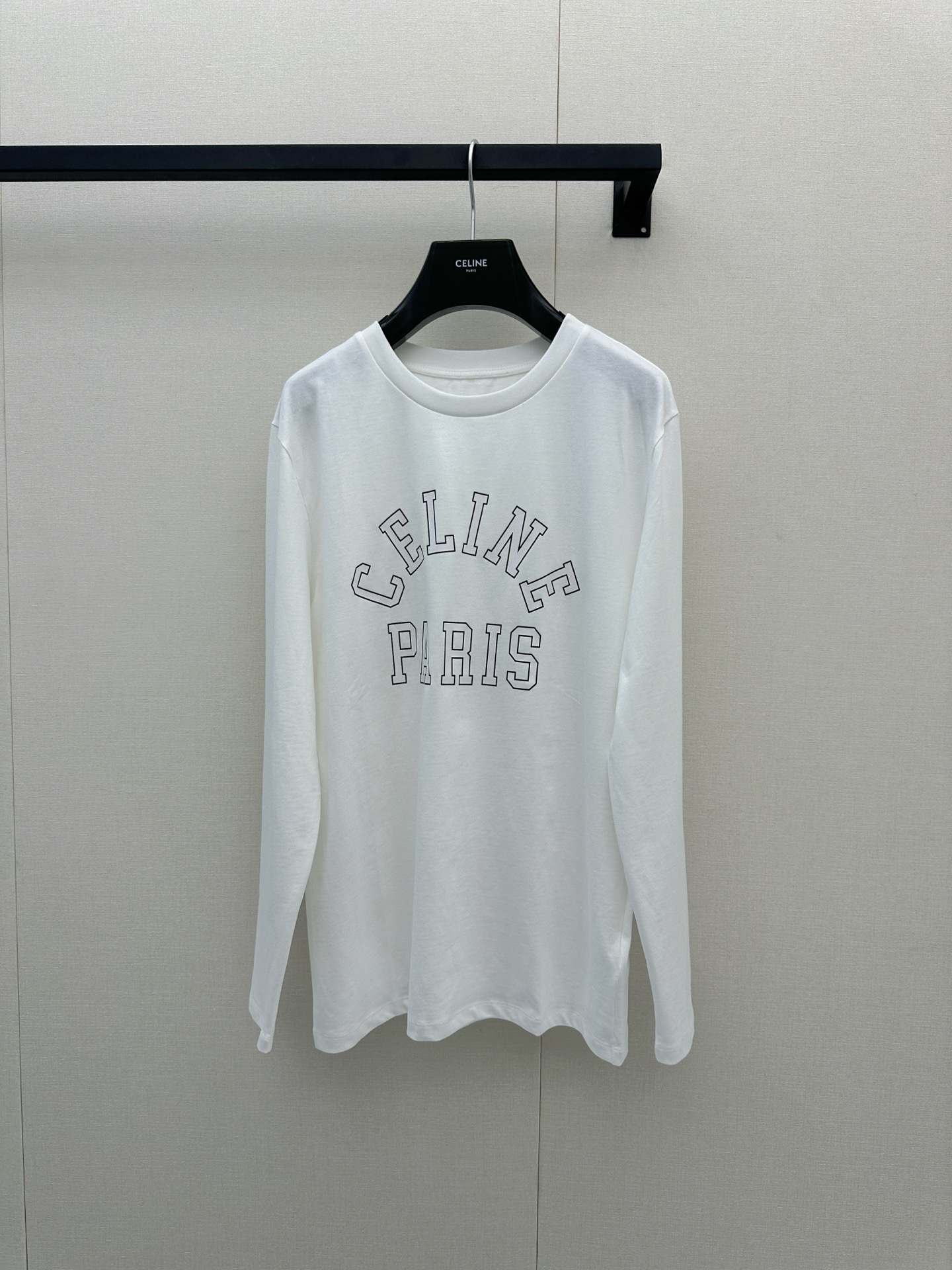 NO:924892,Celine white long-sleeved T-shirt, made of pure cotton jersey fabric, with 'CELINE' outlined in black lines on the chest  PARIS', the font is arranged in a classic sports style arch, and the overall design is simple and recognizable. This T-shirt belongs to the 2025 autumn and winter series. It has a loose fit and is suitable for daily leisure or layering. It is a basic choice for urban fashion people. From the perspective of craftsmanship details, the T-shirt is made of high-weight cotton fabric with a soft touch.  It is soft and not easily deformed. The collar and cuffs are ribbed to improve wearing comfort and durability. The printing part uses environmentally friendly and degradable offset printing materials, and the film is opened by laser engraving to ensure that the pattern is clear, washable and does not fall off. Actual shots of SML products for men and women, celine, tees, t-shirt,19860909Celine白色长袖T恤,采用纯棉平纹针织面料,胸前以黑色线条勾勒出“CELINE PARIS”字样,字体为经典运动风格拱形排列,整体设计简约而富有辨识度.该款T恤属于2025秋冬系列,版型宽松,适合日常休闲或叠穿搭配,是都市时尚人群的基础款选择.从工艺细节来看,该T恤采用高克重棉质面料,触感柔软且不易变形,领口与袖口均采用罗纹收边处理,提升穿着舒适度与耐用性.印花部分使用环保可降解胶印材料,通过激光雕刻菲林开版,确保图案清晰、耐洗不脱落.男女同款SML大货实拍,,celine,tees，t-shirt,,Women's clothing