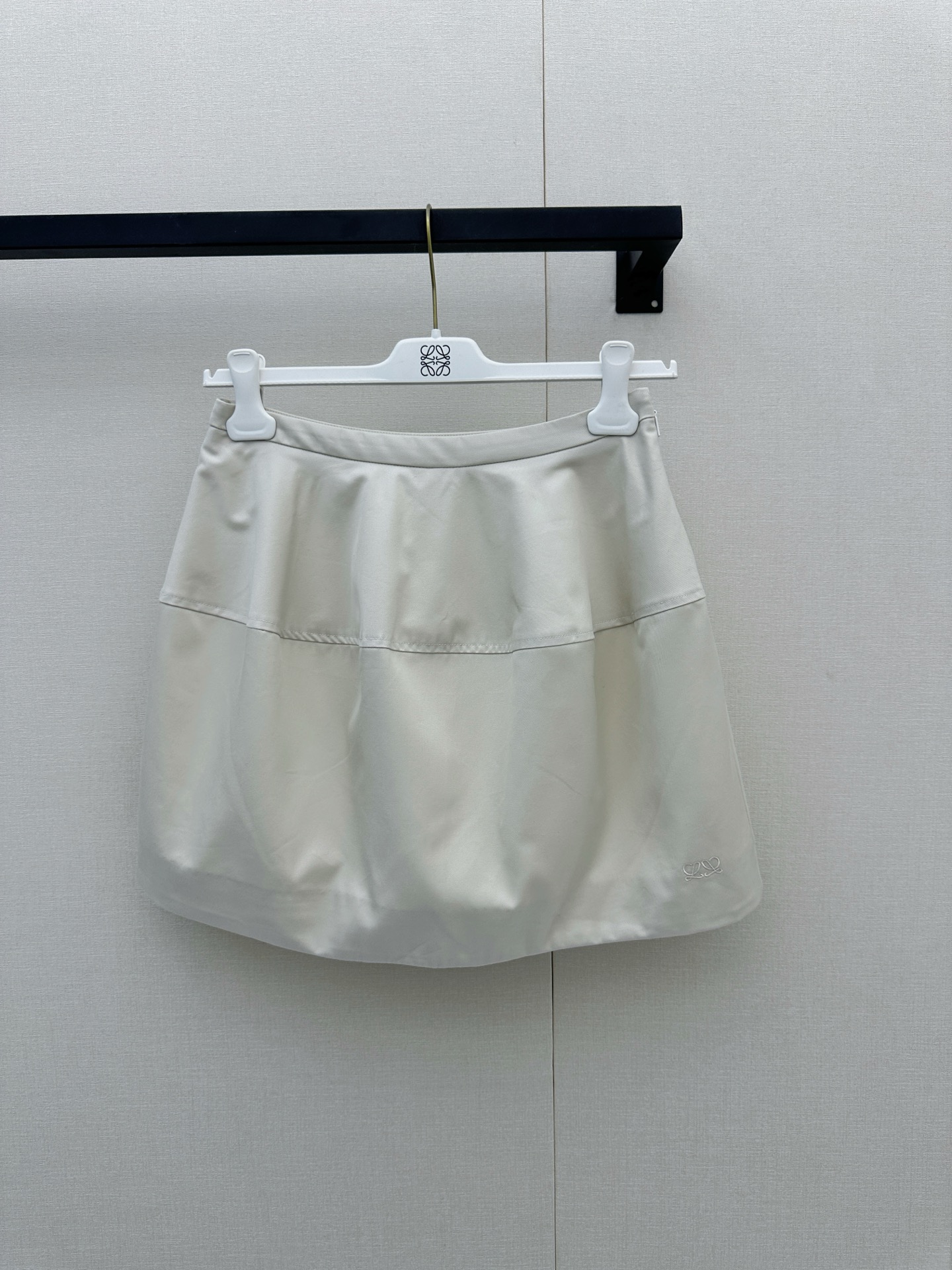NO:947083,Loewe 2026 early spring new style｜Cream mousse A-line skirt, engraved with minimalist high-end romance  Strolling in the artistic atmosphere of the Left Bank of Paris, this Loewe off-white A-line skirt interprets the gentle power of early spring with the purest minimalist lines. It has a texture as delicate as cream mousse, soft and crisp to the touch. The classic A-line shape cleverly accommodates various body shapes and easily lengthens the proportions of the legs. The low-key and exquisite Anagram embroidery on the skirt is like  The artistic signature dropped on the plain canvas silently highlights the brand's ingenuity and French style. Whether paired with a lazy sweater or a neat shirt, it can instantly enhance the fashion of the overall look. It is definitely a versatile artifact in the wardrobe that makes people's hearts beat at a glance. Actual photos of large quantities of sizes SML, loewe, skirts, shirts,19860909Loewe 2026早春新款｜奶油慕斯A字半裙,镌刻极简的高级浪漫 漫步于巴黎左岸的艺术气息中,这款Loewe米白色A字半裙以最纯粹的极简线条,诠释了属于早春的温柔力量.如奶油慕斯般细腻的质感,触感软糯且挺括,经典的A字版型巧妙包容各种身形,轻松拉长腿部比例.裙摆处低调而精致的Anagram刺绣,宛如在素净画布上落下的艺术签名,于无声处彰显品牌的匠心底蕴与法式格调.无论是搭配慵懒的针织衫还是利落的衬衫,都能瞬间提升整体造型的时髦度,绝对是衣橱里那件让人一眼心动的百搭神器.尺码SML大货实拍,,loewe,skirts,shirts,,Women's clothing
