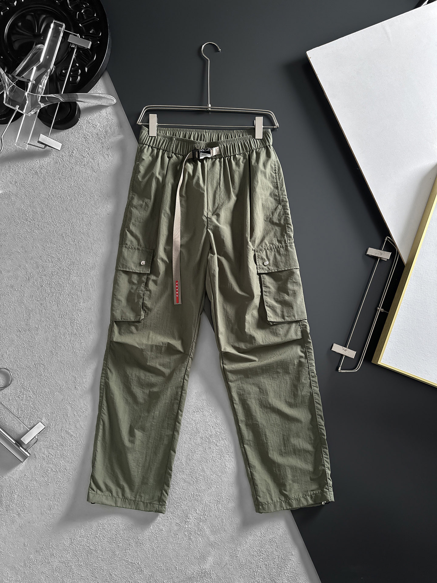NO:870649,PRADA Army Green Overalls | A duet of fashion and practicality. The low-key and calm little army green is both elegant and versatile. The neat straight shape is not flattering on the figure and is comfortable to wear. The large overall pockets on both sides are full of practical attributes and can easily hold various small items. The customized P-family hardware buckles at the waist are the finishing touch, showing luxury in a low-key manner.  .The splicing design of the pants body adds a sense of layering and three-dimensionality. Size M-4XL (shipped next day),, prada, prada,19860909PRADA普拉达 军绿色工装裤 | 时髦与实用的双重奏低调从容的小军绿,既显气质又百搭.利落的直筒版型,不挑身材,穿着舒适自在. 两侧大大的工装口袋,实用属性拉满,能轻松装下各种小物件,腰间开模定制P家专用五金卡扣,更是点睛之笔,低调中彰显奢华 .裤身的拼接设计,增加了层次感和立体感.码数M-4XL（隔天出货）,,prada,prada,,Men's clothing
