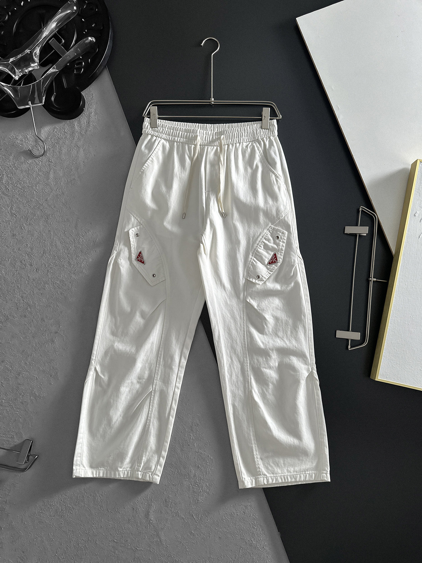 NO:870715,PRADA off-white workwear wide-leg pants | The perfect fusion of casualness and practicality. The gentle and calm small tones can easily create a casual atmosphere. The drawstring design at the waist is easy to adjust and can be worn freely. The design of fake pocket caps on both sides makes the overalls have obvious attributes, and the metal buckle details on the pockets add a bit of toughness. The leg-tie style is neat and makes the legs longer. Size M-2XL (shipped next day),, prada, prada, hats,19860909PRADA普拉达 米白色工装阔腿裤 | 随性与实用的完美融合 温柔又沉稳的小色调,轻松就能营造出随性氛围.腰部的抽绳设计,方便调节,穿着无拘无束 . 两侧假口袋帽设计,工装裤属性显著,而且口袋上的金属扣细节,增添了几分硬朗感.束脚的款式利落又显腿长.码数M-2XL（隔天出货）,,prada,prada,hats,,Men's clothing