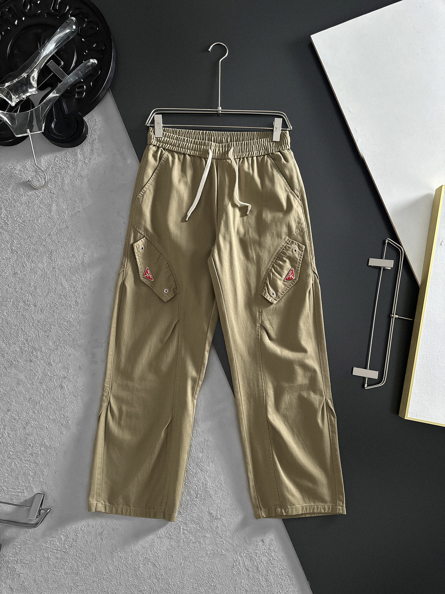 NO:870707,PRADA Khaki workwear wide-leg pants | The perfect fusion of casualness and practicality. The gentle and calm small tones can easily create a casual atmosphere. The drawstring design at the waist is easy to adjust and can be worn freely. The design of fake pocket caps on both sides makes the overalls have obvious attributes, and the metal buckle details on the pockets add a bit of toughness. The leg-tie style is neat and makes the legs longer. Size M-2XL (shipped next day),, prada, prada, hats,19860909PRADA普拉达 卡其色工装阔腿裤 | 随性与实用的完美融合 温柔又沉稳的小色调,轻松就能营造出随性氛围.腰部的抽绳设计,方便调节,穿着无拘无束 . 两侧假口袋帽设计,工装裤属性显著,而且口袋上的金属扣细节,增添了几分硬朗感.束脚的款式利落又显腿长.码数M-2XL（隔天出货）,,prada,prada,hats,,Men's clothing