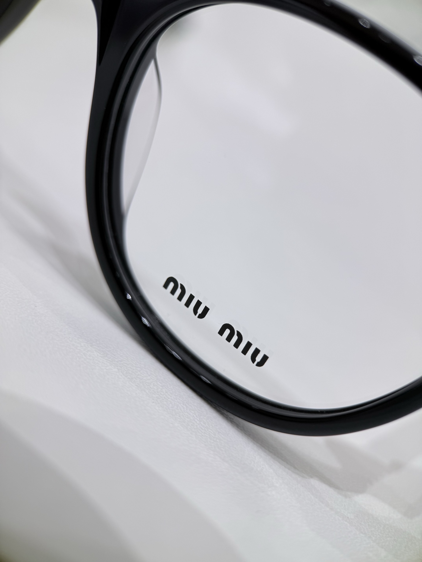MIUMIU\/缪缪VMU02WVF平光镜\/近视眼镜架以匠心型材重构日常光学单品，将轻奢质感与实用主义完美融合，为佩戴者注入灵动风格表达。镜框主体甄选高品质醋酸纤维板材打造，经多道精密工序打磨成型，质地坚韧且不易变形，兼具轻盈质感与亲肤性，长时间佩戴依旧舒适无压。板材纹理自然细腻，光泽度出众，完美契合品牌极简高级的设计语言。镜腿处点缀精致金属铭牌，于细微处彰显奢品辨识度，尽显低调奢华。\n镜片为品牌定制高透光学镜片，光学性能稳定，视物清晰柔和，有效减少视觉疲劳，适配日常长时间佩戴需求。功能性与时尚感兼具，满足不同人群的视力矫正需求。整体设计遵循人体工学原理，镜腿弧度贴合耳际轮廓，佩戴稳固性与舒适度双重提升。\n男女同款\n尺寸：50-18-140\n