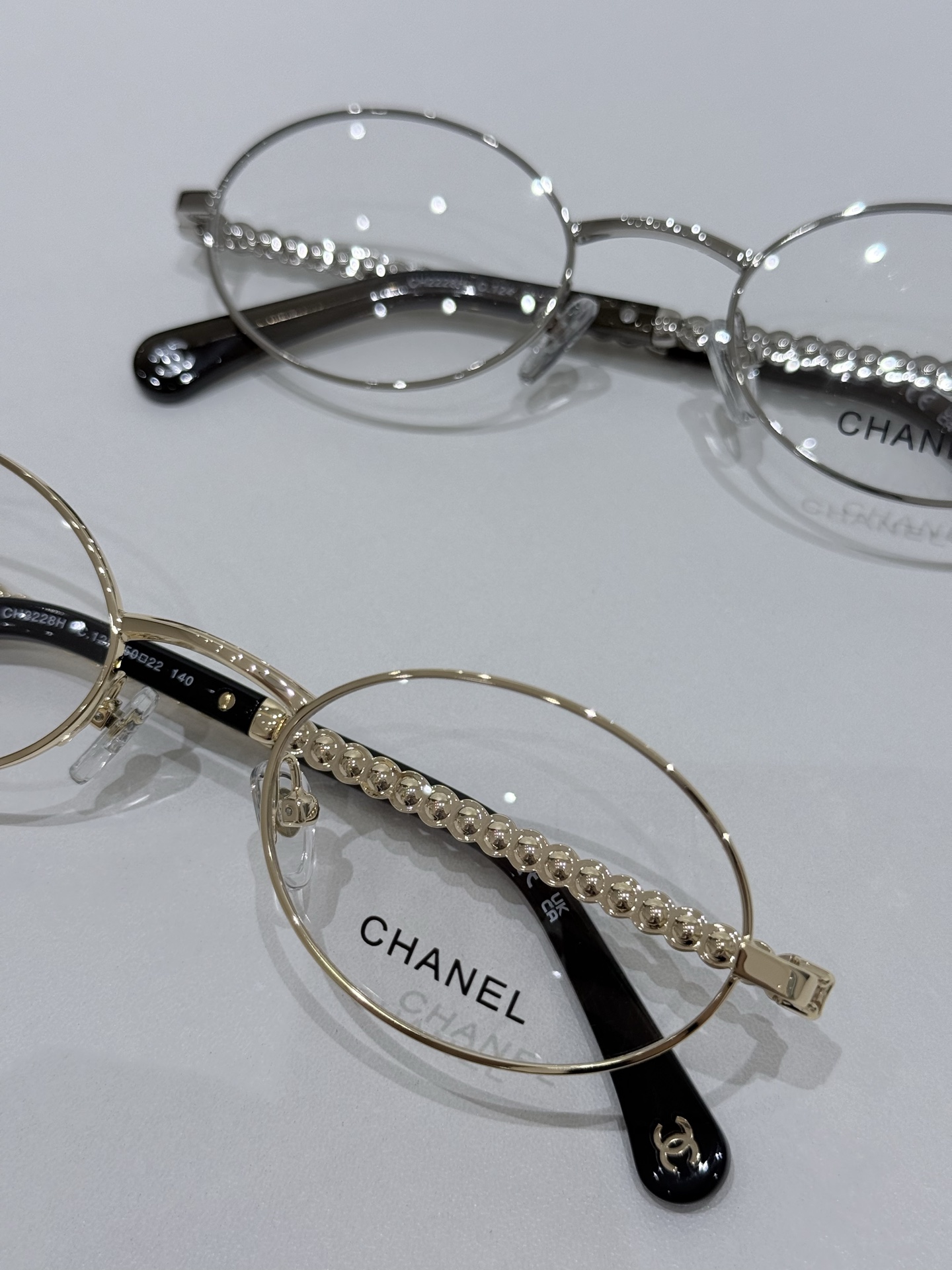 新款CHANEL\/香奈儿CH2228H平光镜\/近视眼镜架以椭圆轮廓重塑经典优雅，将品牌匠心工艺与现代审美融于一体，是日常穿搭与正式场合的理想之选。镜框采用高品质金属型材，经多道精密工序打磨成型，质感细腻且结构稳固，兼具耐用性与轻盈佩戴感。金属表面辅以细腻镀层处理，呈现低调而高级的光泽，尽显品牌对细节的极致追求。镜腿匠心点缀人造珍珠元素，每一颗珍珠均经过严选，色泽温润、排列规整，与金属型材形成精致碰撞，赋予眼镜独特的奢华气质。镜腿侧面暗藏品牌经典标识，于细微处彰显CHANEL的优雅格调，传递低调而隽永的设计语言。\n透明镜片搭配经典椭圆框型，有效修饰脸型，提升面部立体感，同时满足日常光学佩戴需求。轻盈的金属型材搭配精致珍珠细节，兼顾舒适与美观，即使长时间佩戴也无负担。镜腿处金属与人造珍珠的精妙组合，将法式优雅与现代工艺完美融合，既是实用的光学配饰，也是彰显品味的时尚符号。\n尺寸：50-22-140\n