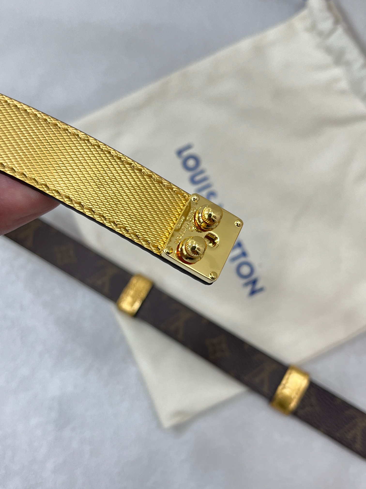 咖色边Serrures 腰带取材牛皮革，以耀目 S-Lock 搭扣致意品牌传统硬箱。路易威登标识压纹和 