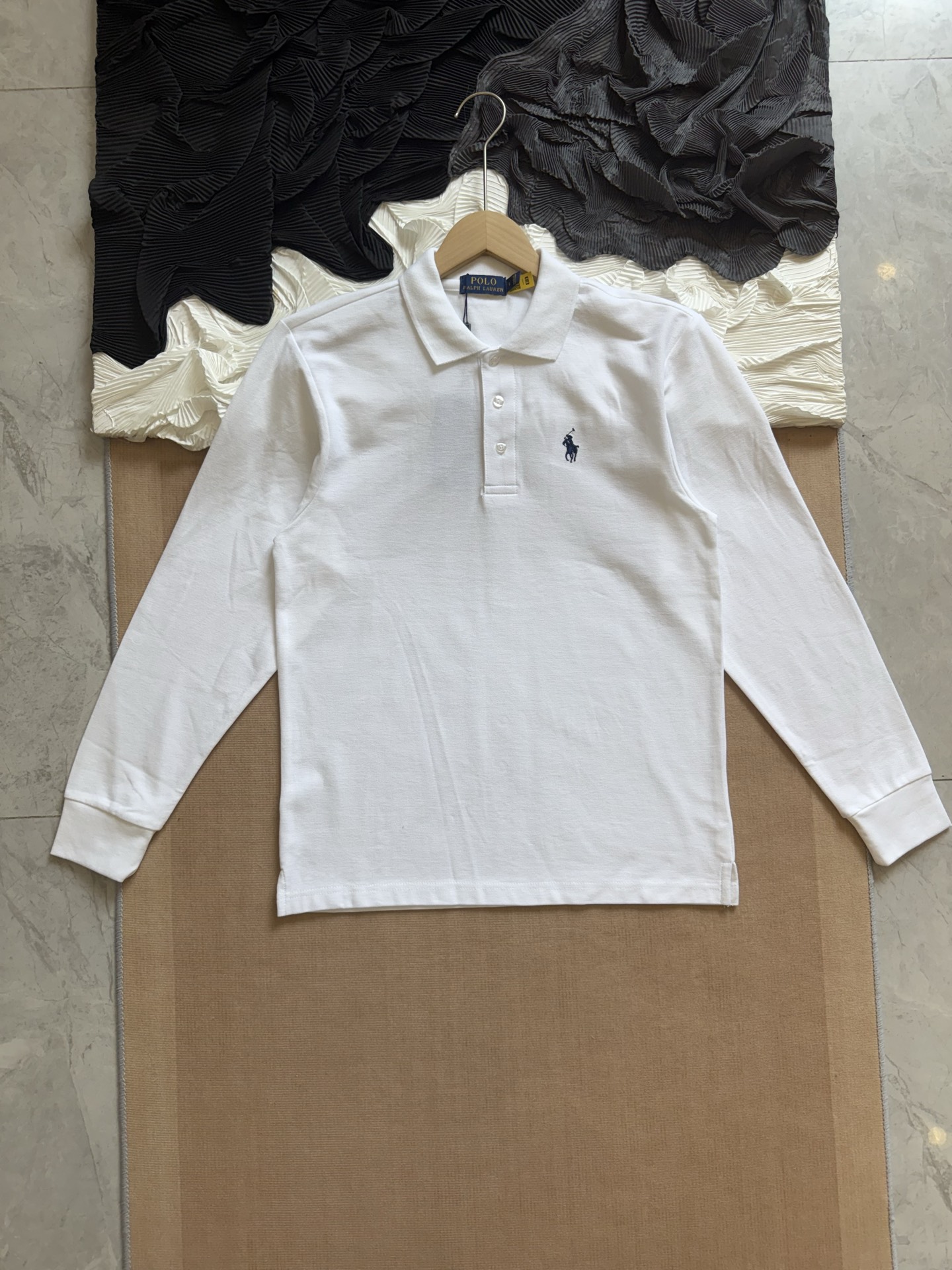 💰110
Ralph Lauren拉夫劳伦 三色经典小马刺绣 休闲基础款长袖Polo衫

采用高支数240g纯棉珠地布面料，透气不闷热，具备良好弹性与贴肤质感。无论是春夏单穿，还是秋冬内搭，都能保持干爽舒适，为日常穿搭增添轻盈体验。

每一处缝合均采用双线走针技术，牢固且耐穿。下摆采用双侧开叉设计，增强活动灵活度的同时不失版型利落。领口三粒扣设计，经典中带有变化，细节之处尽显品位。

胸前标志性Logo刺绣，黑色款搭配热烈红标，白色款搭配深蓝刺绣，凸显品牌辨识度的同时，又不失简洁大气。后领内衬带品牌织标，精致感满满。

经典色系，可正式可休闲，满足多种穿搭场景，修身剪裁，挺括有型，适合多种体型；
品牌象征 + 高品质工艺，体现穿着者的生活品位与审美高度，不止是一件Polo衫，更是日常中的质感表达。

-颜色：黑色、白色、藏青
-尺码：S-2XL

尺码   胸围  衣长  肩宽    推荐体重（斤）
 S       108     66     47     100-115
 M       112     69     48     115-130
 L        116     72      50     130-150
 XL      120     75      51     150-175
 XXL    124     78     53      175-205