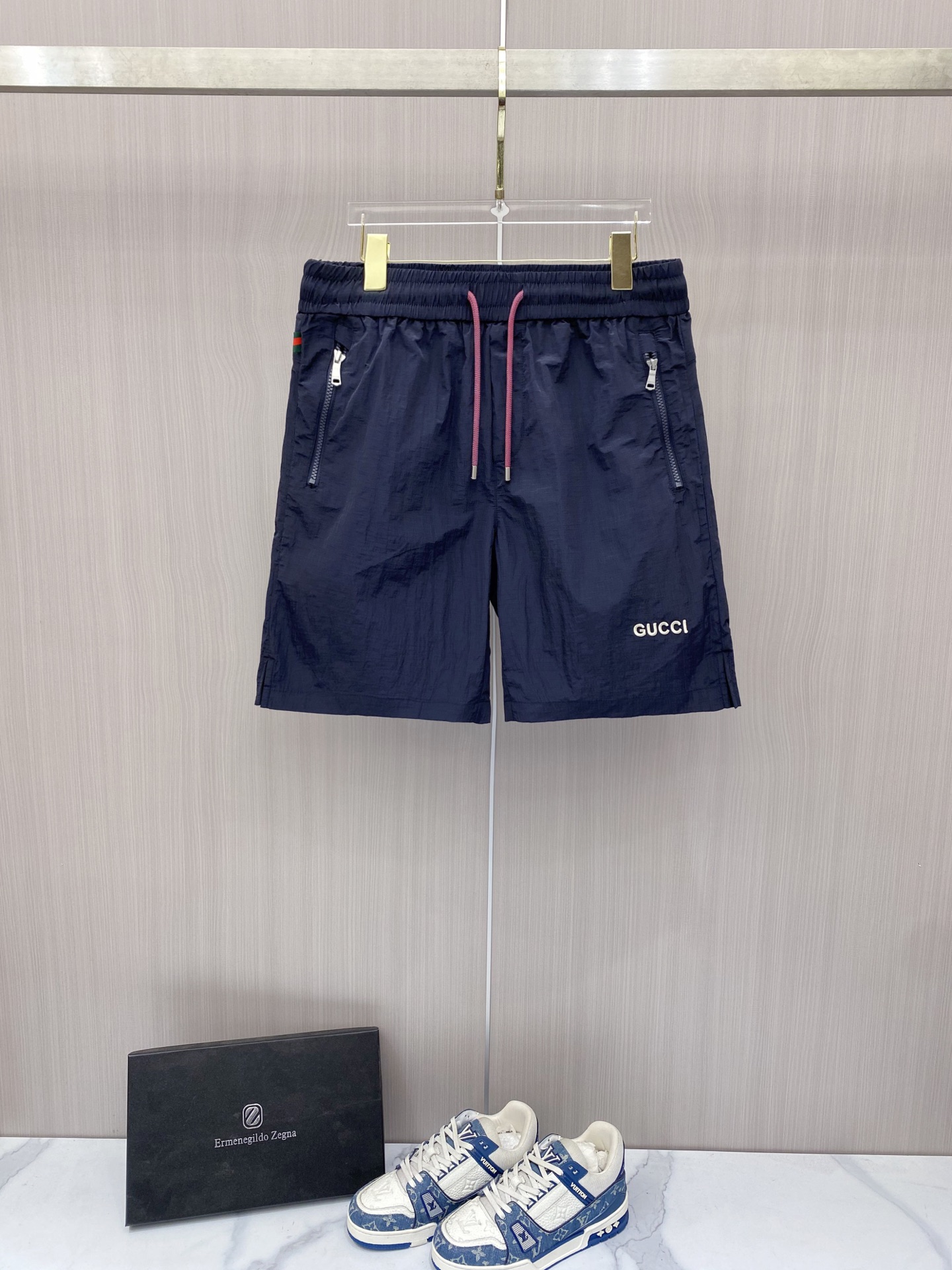 NO:848774,Gucci Gucci  The 2026ss summer limited edition contrasting color drawstring casual shorts cleverly combine the brand's classic webbing elements with refreshing functional style. They are available in navy blue/off-white and are suitable for a variety of summer styles. Made of high-density wrinkled nylon fabric, they are lightweight and breathable. The upper body is draped and stylish, without fear of stuffiness and wrinkles; the waistband is designed with a contrasting pink drawstring  Designed with classic red and green webbing details on the side, the brand genes can be recognized at a glance. The front zipper pocket is both practical and neat. The GUCCI letter logo on the front and the metal badge pocket on the back are low-key. The loose straight version modifies the leg shape. Whether you are commuting in the city or traveling on vacation, you can easily create a relaxed and noble summer style.  Color: navy blue, off-white, size 48-56,,gucci,shorts,19860909Gucci 古奇 2026ss夏季限定撞色抽绳休闲短裤,将品牌经典织带元素与清爽机能风巧妙融合,藏青/米白双色可选,适配多元夏日风格.甄选高密皱感尼龙面料打造,自带轻量透气属性,上身垂坠有型,无惧闷热与褶皱；腰头撞色粉调抽绳设计,搭配侧边经典红绿织带细节,一眼识别品牌基因.前侧拉链口袋兼顾实用与利落,正面GUCCI字母标识与背面金属徽章口袋低调点题,宽松直筒版型修饰腿型,无论是都市通勤还是度假出行,都能轻松塑造松弛显贵的夏日格调. 颜色藏青 米白 码数48-56,,gucci,shorts,,Men's clothing