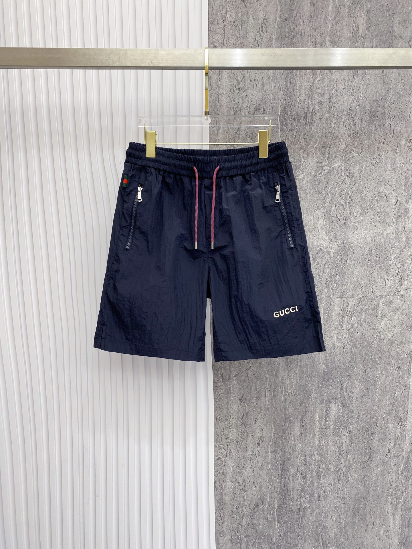 NO:842806,Gucci Gucci  The 2026ss summer limited edition contrasting color drawstring casual shorts cleverly combine the brand's classic webbing elements with refreshing functional style. They are available in navy blue/off-white and are suitable for a variety of summer styles. Made of high-density wrinkled nylon fabric, they are lightweight and breathable. The upper body is draped and stylish, without fear of stuffiness and wrinkles; the waistband is designed with a contrasting pink drawstring  Designed with classic red and green webbing details on the side, the brand genes can be recognized at a glance. The front zipper pocket is both practical and neat. The GUCCI letter logo on the front and the metal badge pocket on the back are low-key. The loose straight version modifies the leg shape. Whether you are commuting in the city or traveling on vacation, you can easily create a relaxed and noble summer style.  Color: navy blue, off-white, size 48-56,,gucci,shorts,19860909Gucci 古奇 2026ss夏季限定撞色抽绳休闲短裤,将品牌经典织带元素与清爽机能风巧妙融合,藏青/米白双色可选,适配多元夏日风格.甄选高密皱感尼龙面料打造,自带轻量透气属性,上身垂坠有型,无惧闷热与褶皱；腰头撞色粉调抽绳设计,搭配侧边经典红绿织带细节,一眼识别品牌基因.前侧拉链口袋兼顾实用与利落,正面GUCCI字母标识与背面金属徽章口袋低调点题,宽松直筒版型修饰腿型,无论是都市通勤还是度假出行,都能轻松塑造松弛显贵的夏日格调. 颜色藏青 米白 码数48-56,,gucci,shorts,,Men's clothing