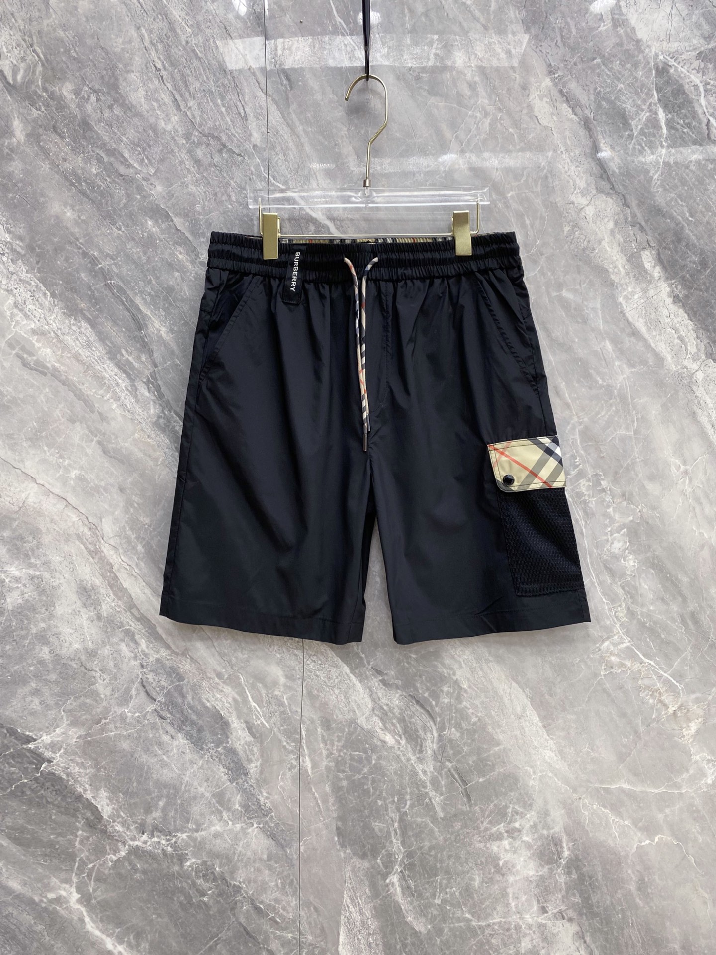 NO:861038,Burberry [2026 Spring and Summer New Style · Burberry Plaid Spliced ​​Casual Shorts] The classic plaid reshapes the summer style, giving you a relaxed and high-end feel throughout the summer!  [Customized lightweight fabric] Crisp and breathable, with anti-wrinkle and drapey feel, it will not collapse after sitting for a long time or sweating, so it is zero burden to wear in summer [Classic plaid splicing] Retro plaid pockets on the side + mesh splicing design, full of brand recognition, low-key and self-recognizable [full of details and texture]  Waistband with woven logo of the same brand, paired with classic plaid drawstring, taking into account practicality and brand tone, suitable for daily/commuting/leisure scenes. [Two colors optional] Gentle off-white/versatile pure black, suitable for diverse summer wear, T-shirts/POLO/shirts can be worn with any combination to create a high-quality feel.  Size 48-56,,burberry,burberry,shorts,shirts,tees,t-shirt,19860909巴宝莉【2026春夏新款 · Burberry 格纹拼接休闲短裤】 经典格纹重塑夏日格调,承包你整个夏天的松弛高级感！【定制轻薄面料】挺括透气,自带抗皱垂坠感,久坐不塌、出汗不粘身,夏日穿着零负担【经典格纹拼接】侧边复古格纹口袋+网纱拼接设计,品牌辨识度拉满,低调中自带辨识度【细节质感拉满】同品牌标识织标腰头,搭配经典格纹抽绳,兼顾实用性与品牌调性,日常/通勤/休闲场景都适配【双色可选】温柔米白/百搭纯黑,适配多元夏日穿搭,T恤/POLO/衬衫随便搭都能穿出质感 码数48-56,,burberry,burberry,shorts,shirts,tees，t-shirt,,Men's clothing
