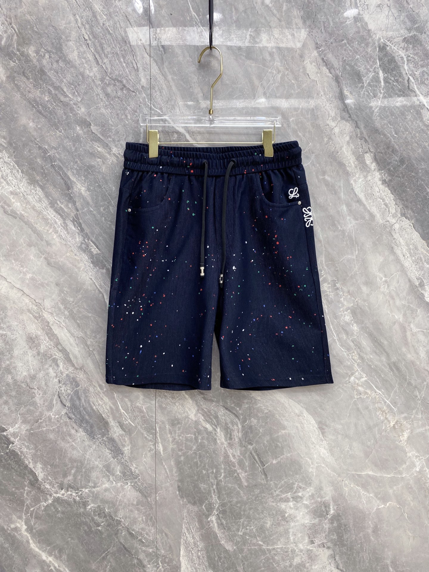 NO:861006,| LOEWE 2026 new spring and summer casual shorts with splash embroidery. An artistic spring and summer limited edition. Colorful splash printing with iconic Anagram embroidery hides high luxury in the details. Selected breathable drape fabrics, the upper body is soft and skin-friendly, has a cool feeling without sweating, and is loosely cut to hide the flesh and is neat. Elastic drawstring waist design, adapts to a variety of body shapes, and has no sense of restraint in daily wear.  The practical pockets on both sides take into account both appearance and practicality, and are available in three colors: white/navy blue/black. You can easily control casual, sophisticated, and street styles, and are the highlights of your outfit throughout the summer. Size 48~56,,loewe,loewe,shorts,19860909| LOEWE 罗意威 2026春夏新款 泼墨刺绣休闲短裤 自带艺术感的春夏限定款,彩色泼墨印花搭配标志性Anagram刺绣,把高奢调性藏在细节里 甄选透气垂感面料,上身柔软亲肤,自带凉感不闷汗,宽松剪裁藏肉又利落 松紧抽绳腰头设计,适配多种身形,日常穿零束缚感 双侧实用口袋兼顾颜值与实用性,白/藏蓝/黑三色可选,轻松驾驭休闲、轻熟、街头多种风格,承包你整个夏天的穿搭亮点 码数48~56,,loewe,loewe,shorts,,Men's clothing