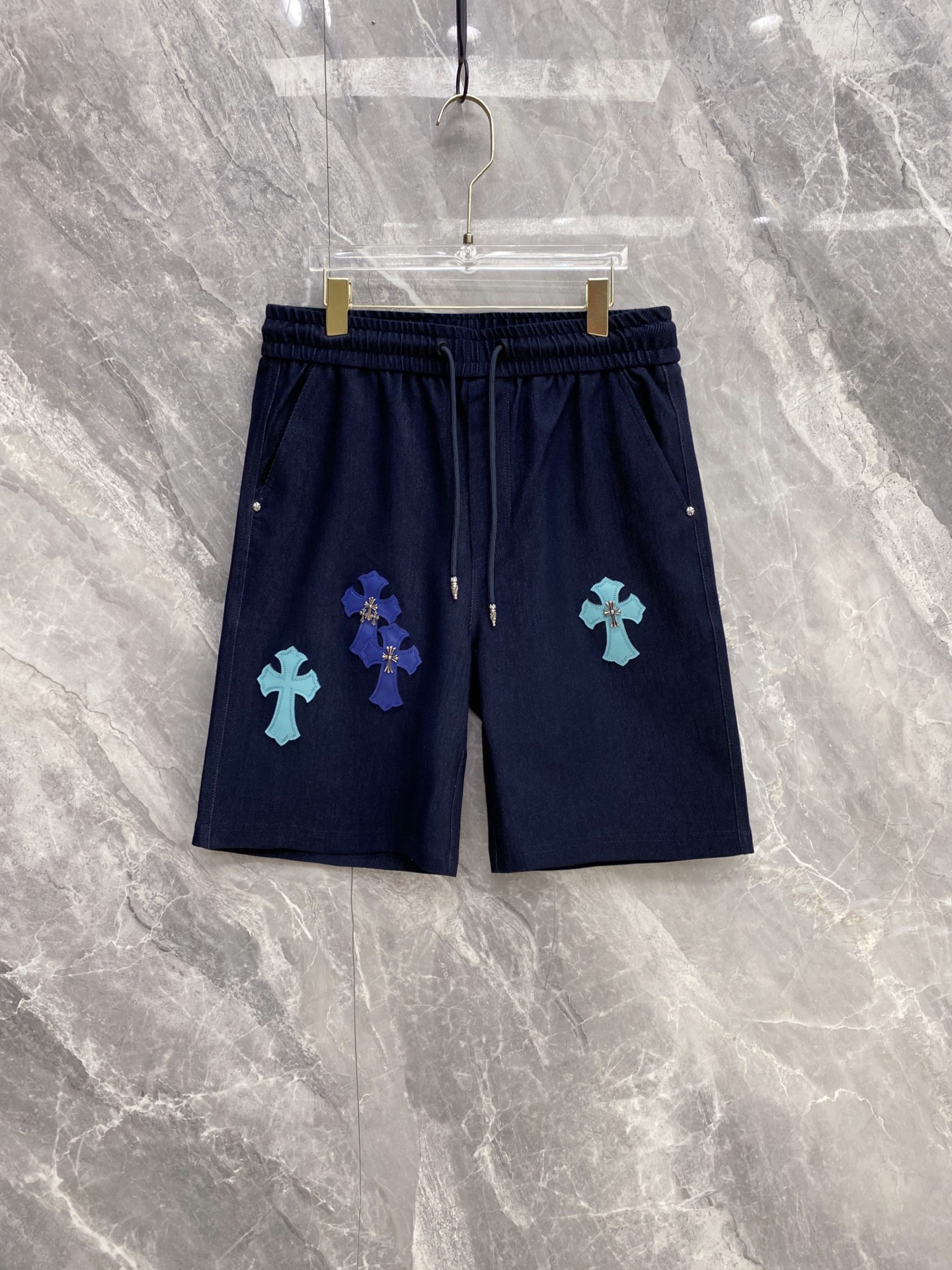 NO:861028,| CHROME HEARTS 2026 spring and summer new color cross leather label casual shorts. A must-have spring and summer limited edition for American high-street players. The contrasting color cross leather label is matched with metal rivet details. It has a dark and luxurious sense of recognition and completes the iconic style of CHROME HEARTS. The breathable drape fabric is selected, the upper body is soft and skin-friendly, it has a cool feeling without sweating, and the loose cut hides the flesh and is neat.  Elastic drawstring waistband + metal head drawstring, full of details, adaptable to various body shapes, no sense of restraint in daily wear. Practical pockets on both sides take into account both appearance and practicality. White/navy blue/black are available in three colors. It can easily control various styles of street, casual and casual, and can be your outfit highlight throughout the summer. Size 48~56,,chrome hearts,chrome hearts,shorts,19860909| CHROME HEARTS 克罗心 2026春夏新款 彩色十字架皮标休闲短裤 美式高街玩家必入的春夏限定款,撞色十字架皮标搭配金属铆钉细节,自带暗黑奢潮辨识度,把克罗心标志性风格拉满 甄选透气垂感面料,上身柔软亲肤,自带凉感不闷汗,宽松剪裁藏肉又利落 松紧抽绳腰头+金属头抽绳,细节感拉满,适配多种身形,日常穿零束缚感 双侧实用口袋兼顾颜值与实用性,白/藏蓝/黑三色可选,轻松驾驭街头、休闲、轻熟多种风格,承包你整个夏天的穿搭亮点 码数48~56,,chrome hearts,chrome hearts,shorts,,Men's clothing